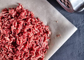 Raw ground beef next to a meat grinder