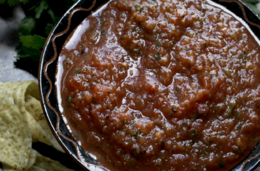 Restaurant style salsa with apple cider vinegar in a black bowl, viewed from above