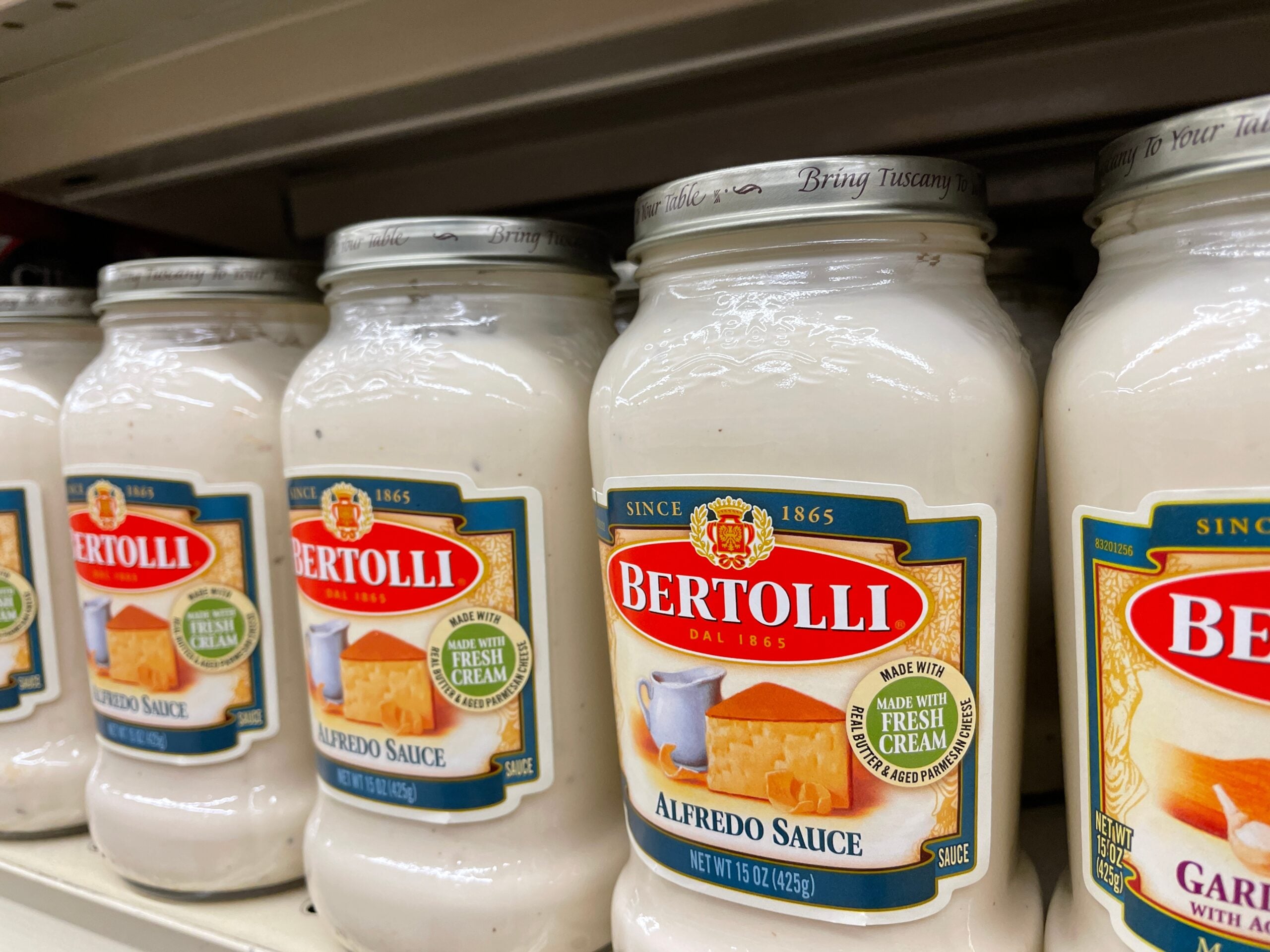 Alfredo sauce jars on a grocery store shelf.