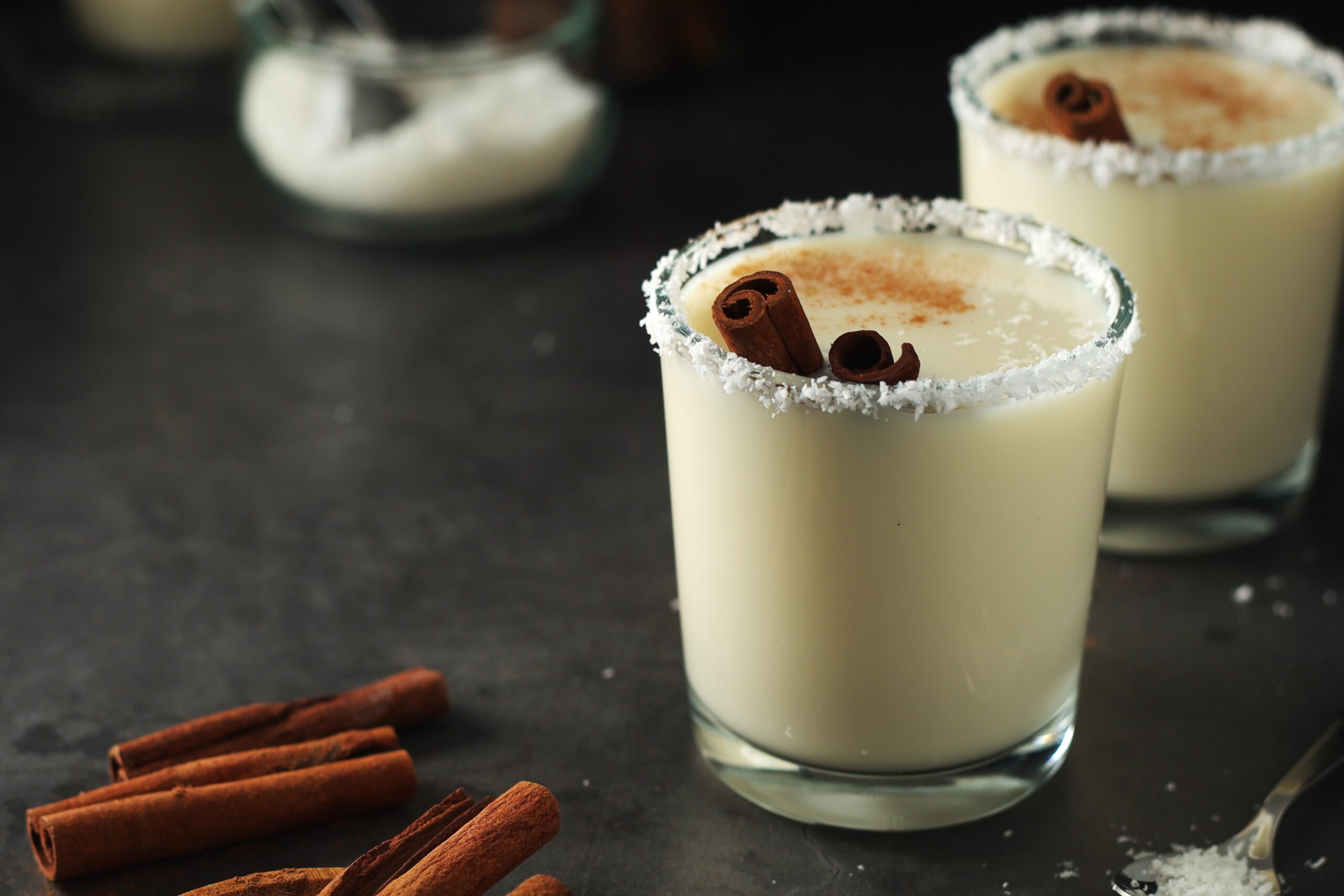 Macro shot of a pair of glasses of boozy vanilla milkshake with cinnamon.