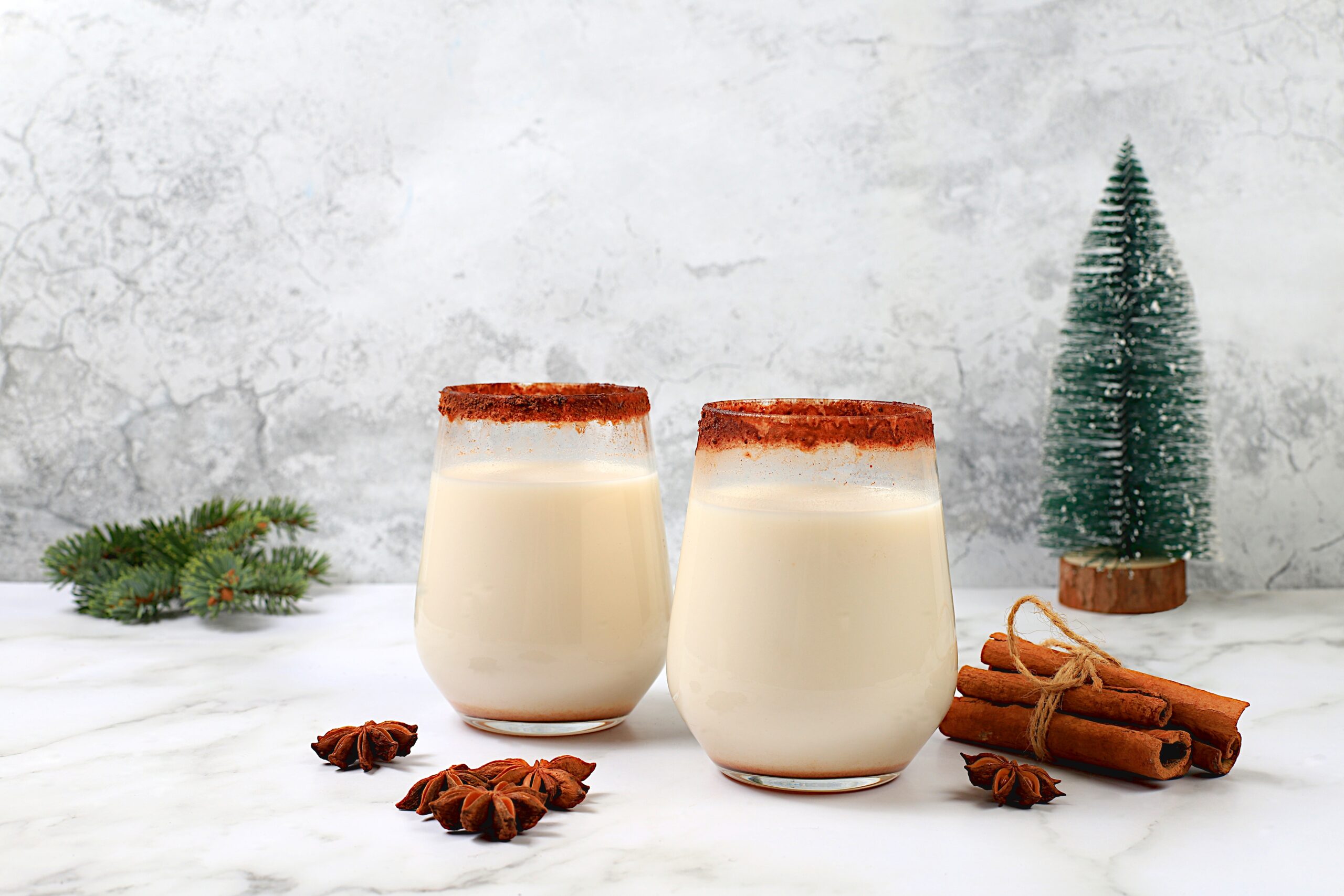 Two eggnog glasses on a Christmas background. 