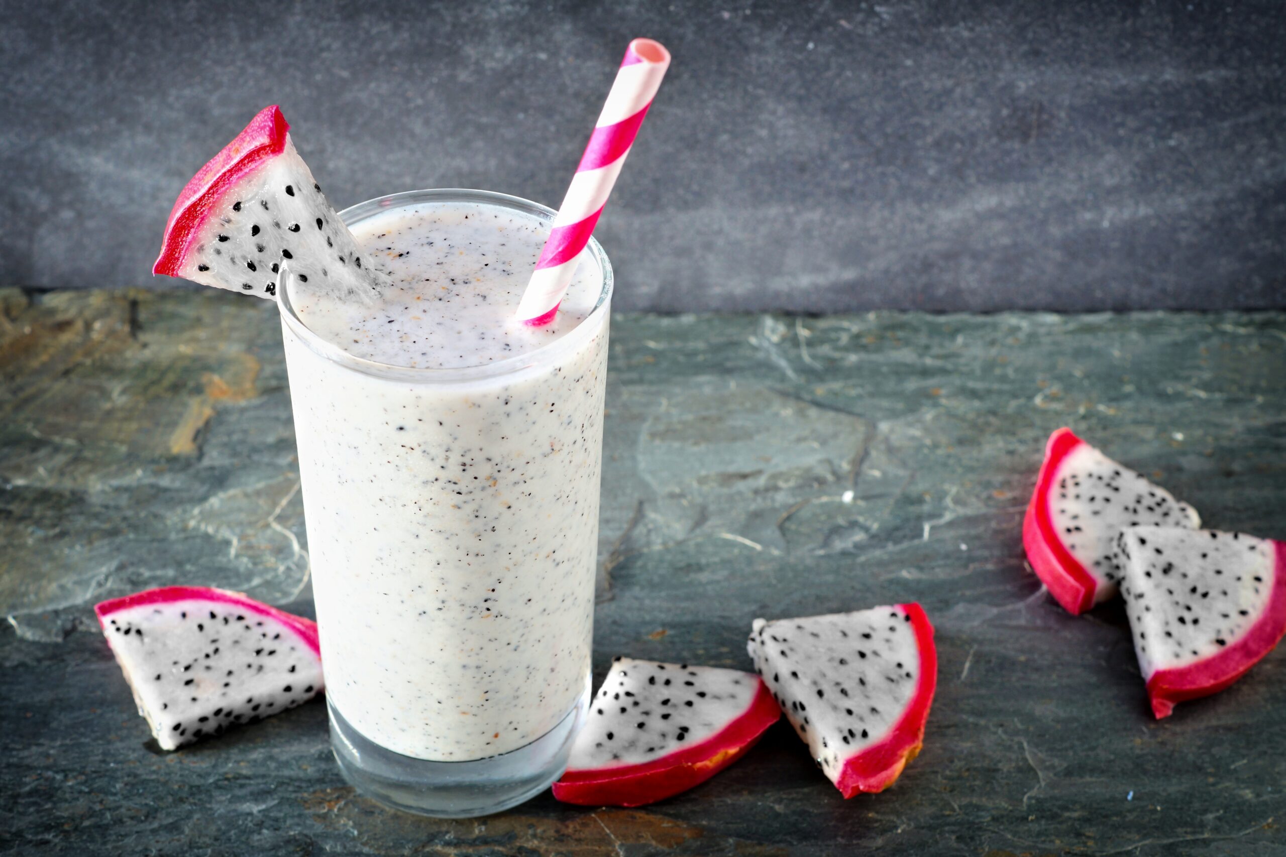 A rustic backdrop showcasing a dragonfruit smoothie surrounded by some dragonfruit slices. 