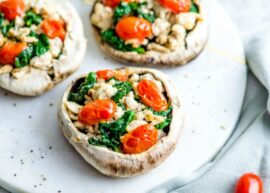 A plate of turkey stuffed portobello mushrooms with grape tomatoes and spinach.
