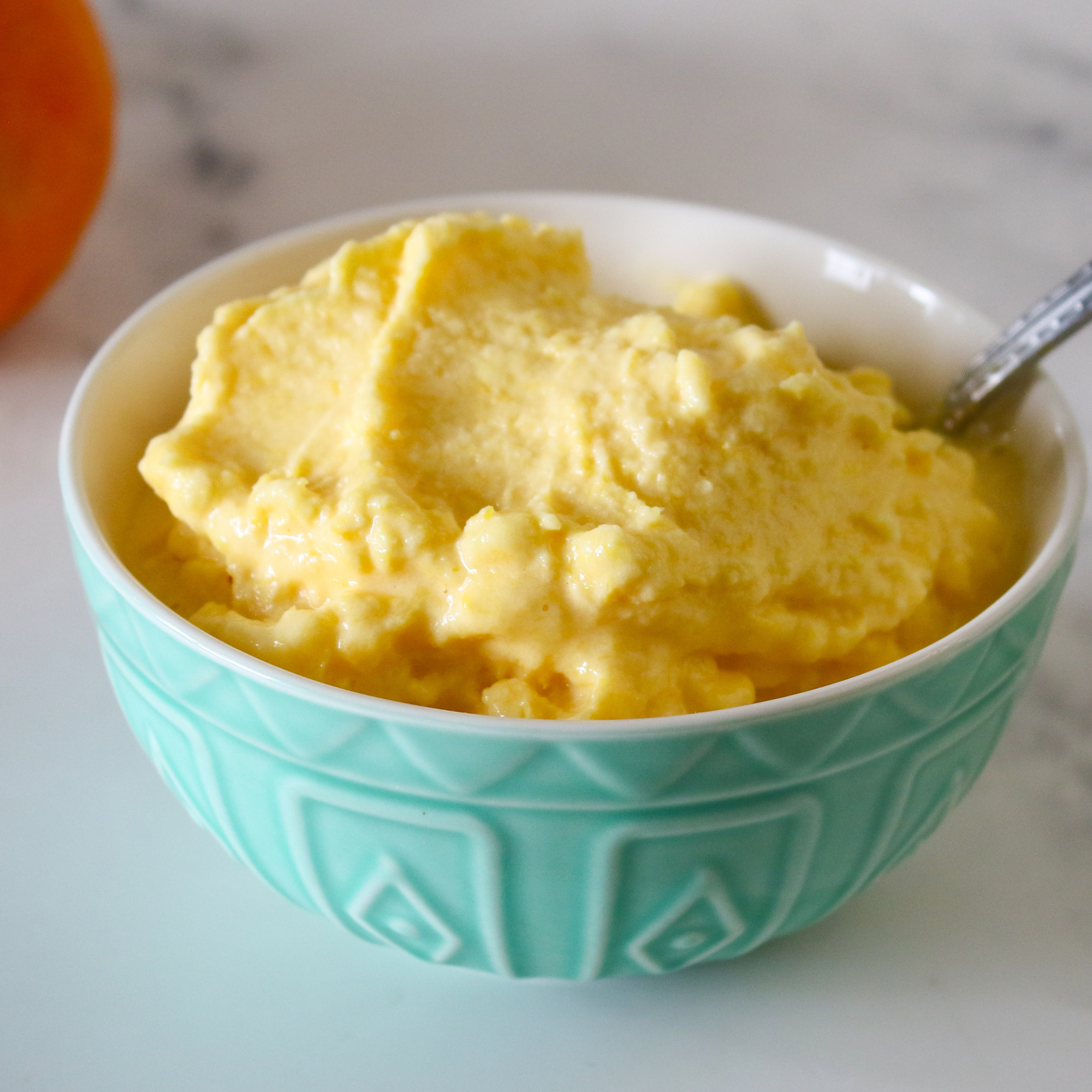 A bowl of homemade orange sorbet in a light green bowl.