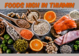 An arrangement of foods high in time sitting on a wooden surface. The text reads, "Foods High In Thiamin."