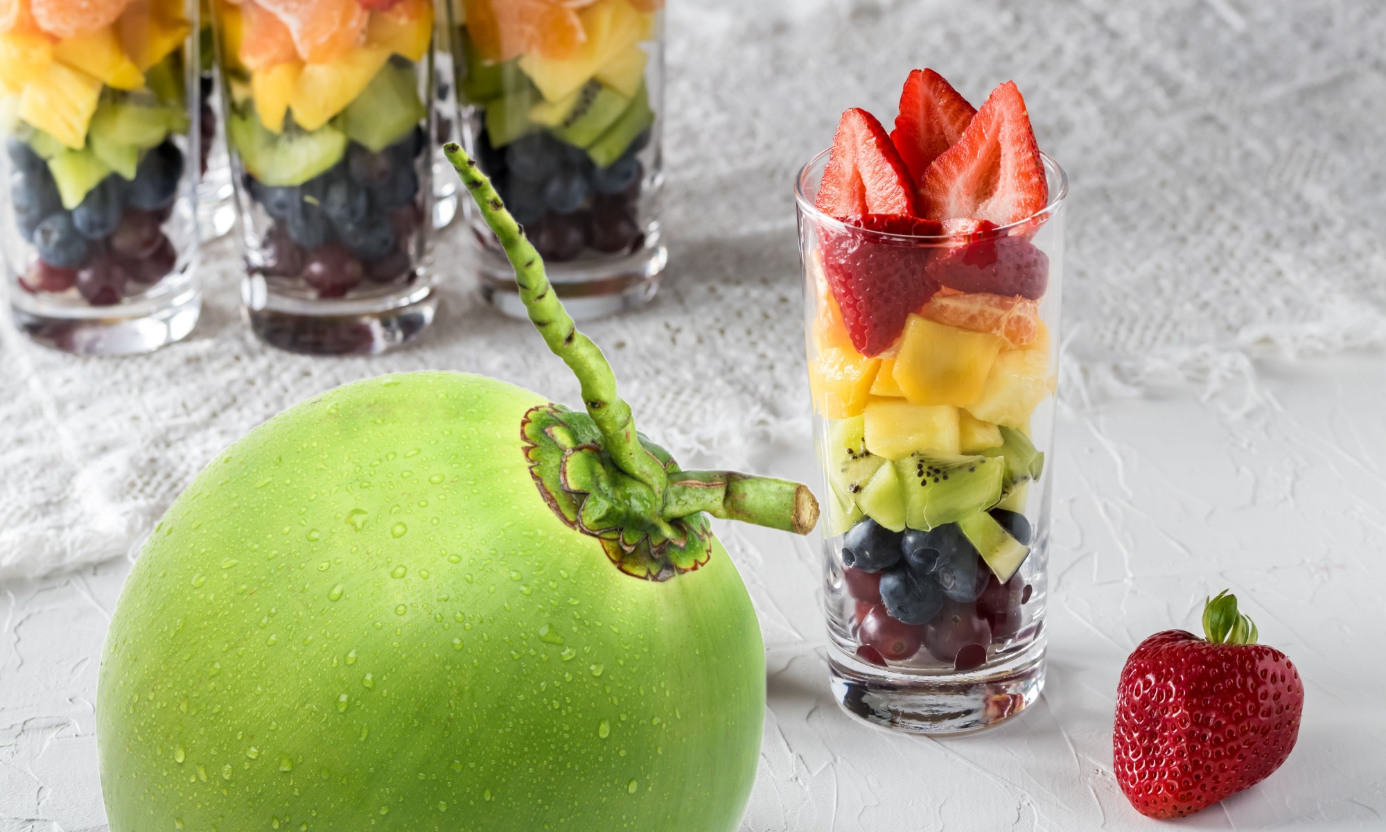 Rainbow, Coconut, Water. Glasses with layered fruit in rainbow colors following ROYGBIV and a coconut, representing rainbow coconut water.