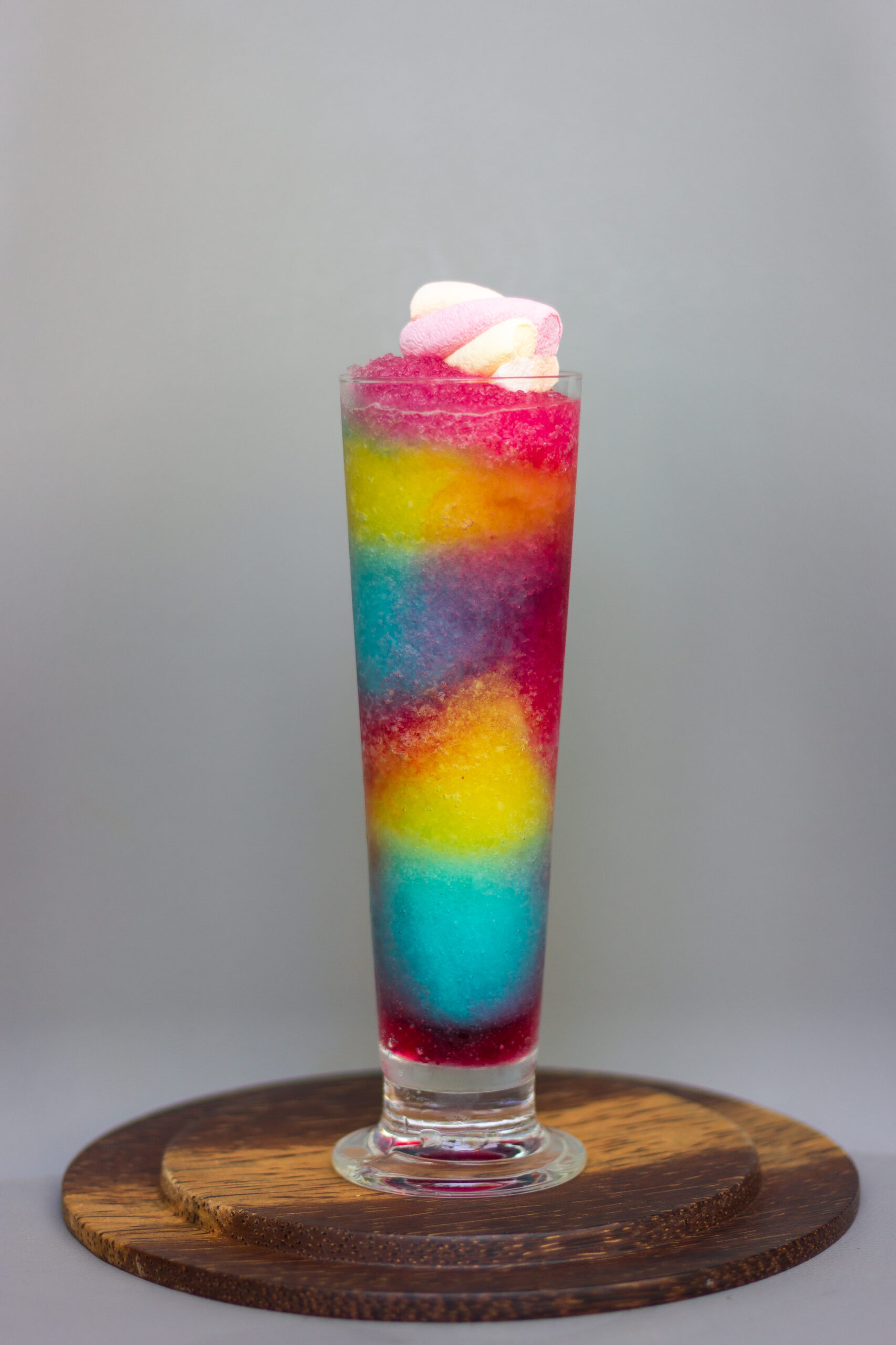 Healthy,Rainbow,Smoothie,In,Glass,With,Marshmallow,On,Grey,Background,healthy A wooden board displayinng a tall glass full of rainbow smoothie.