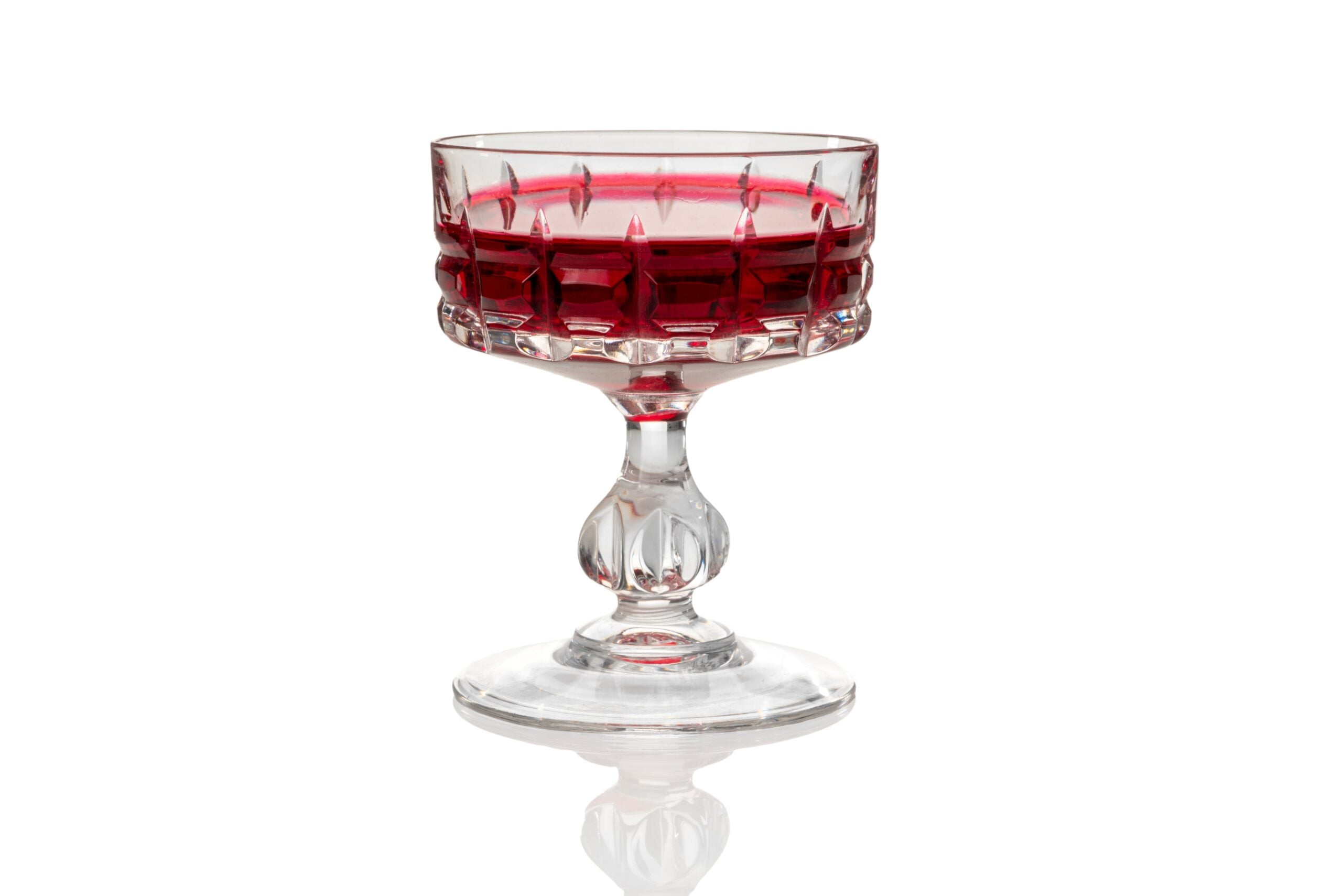 An isolated vintage glass filled with cassis.