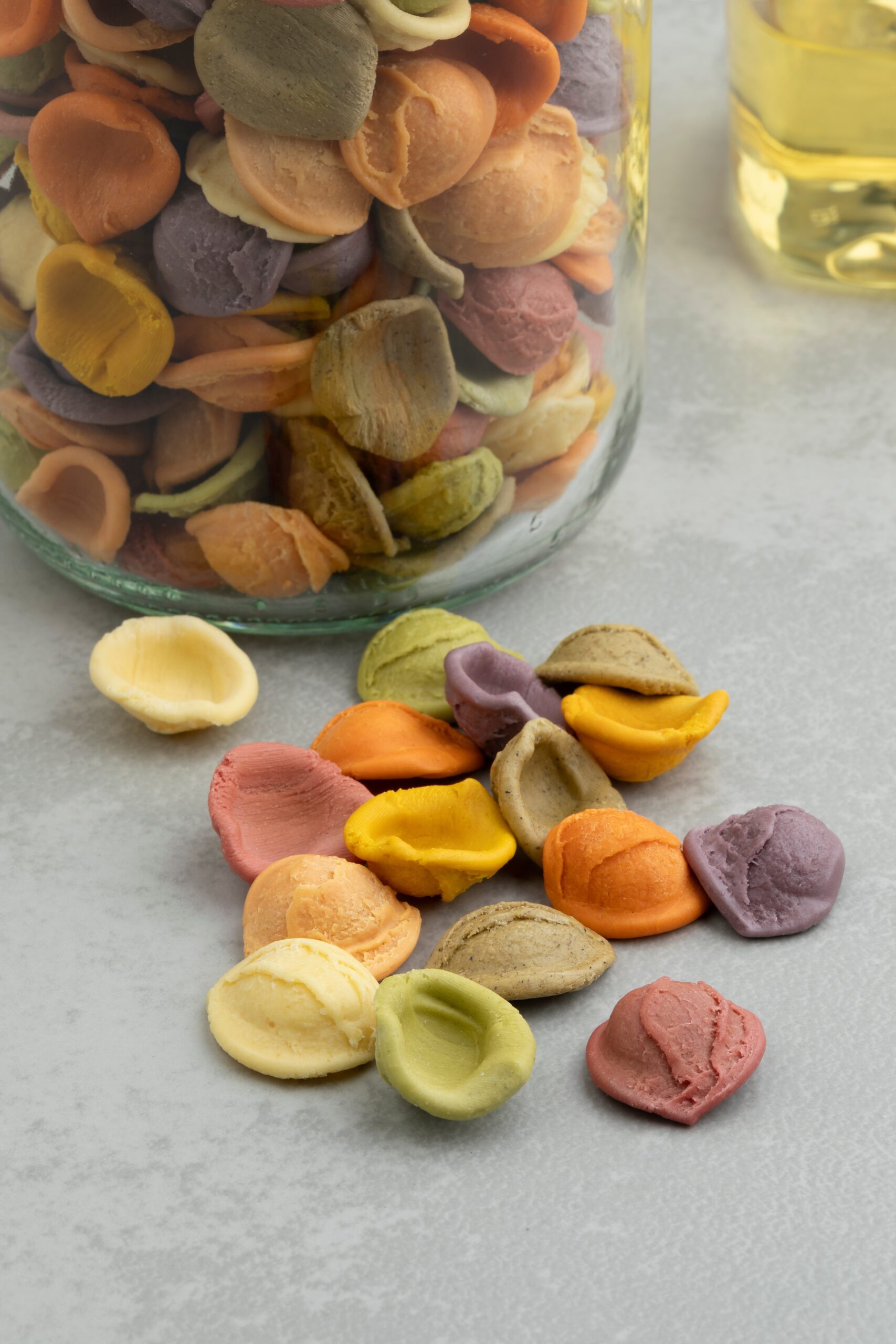 A jar overflowing with rainbow raw pasta. 