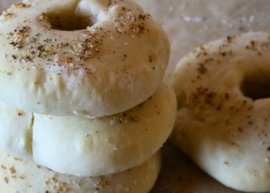 3 stacked bagels next to one bagel on a flat surface