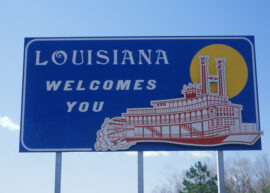 Blue road sign reads "Louisiana Welcomes You" with a red steamboat on it
