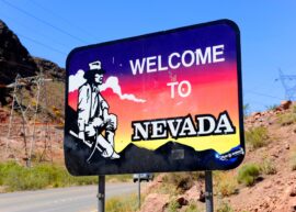 Sign says "welcome to Nevada" with a highway in the background