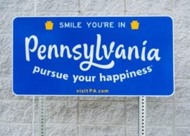 "Smile you're in Pennsylvania pursue your happiness" on a blue sign
