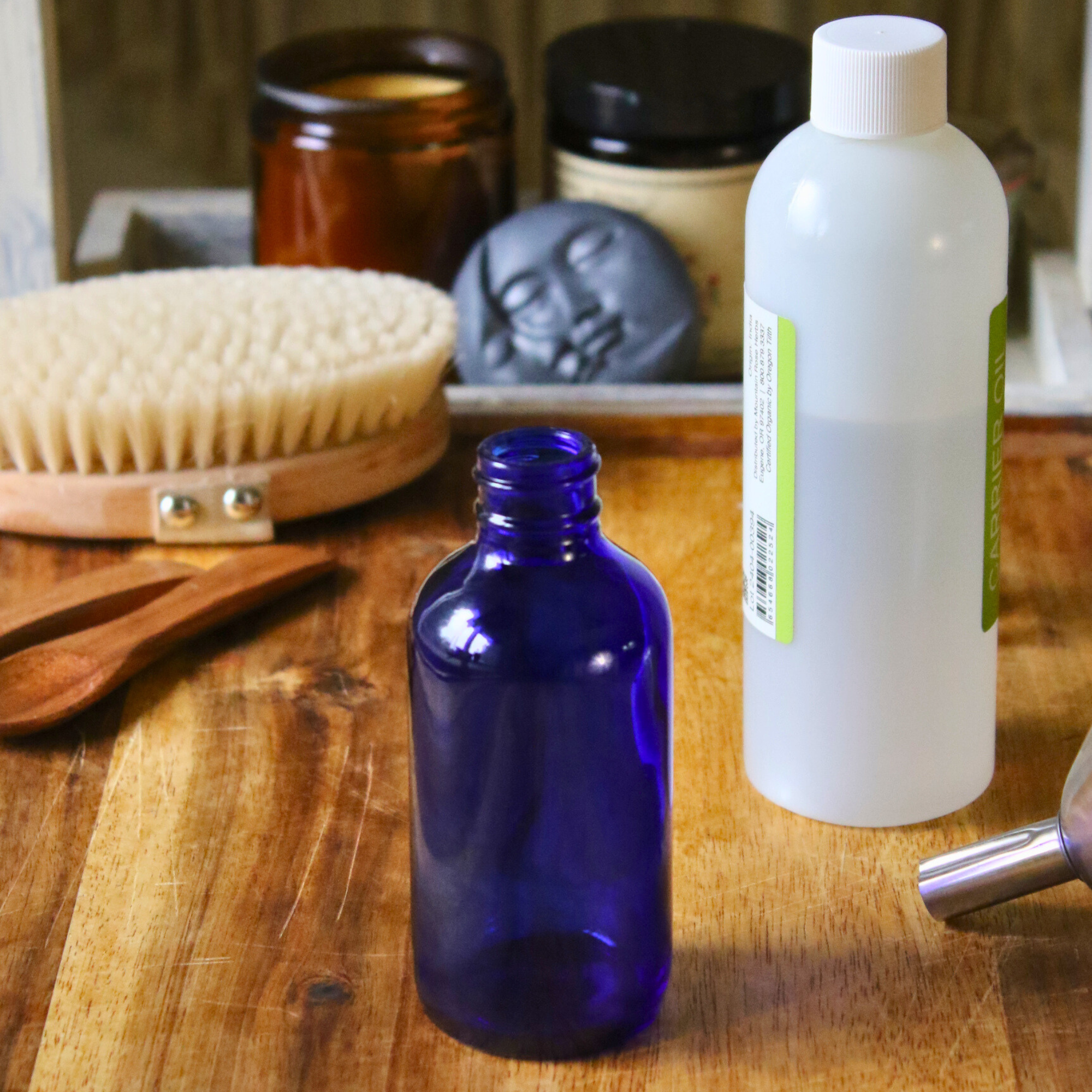 An empty blue bottle next to a bottle of a carrier oil. 