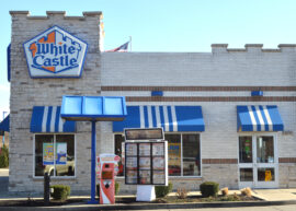 Exterior of a White Castle restaurant with blue awnings and a drive-thru menu.