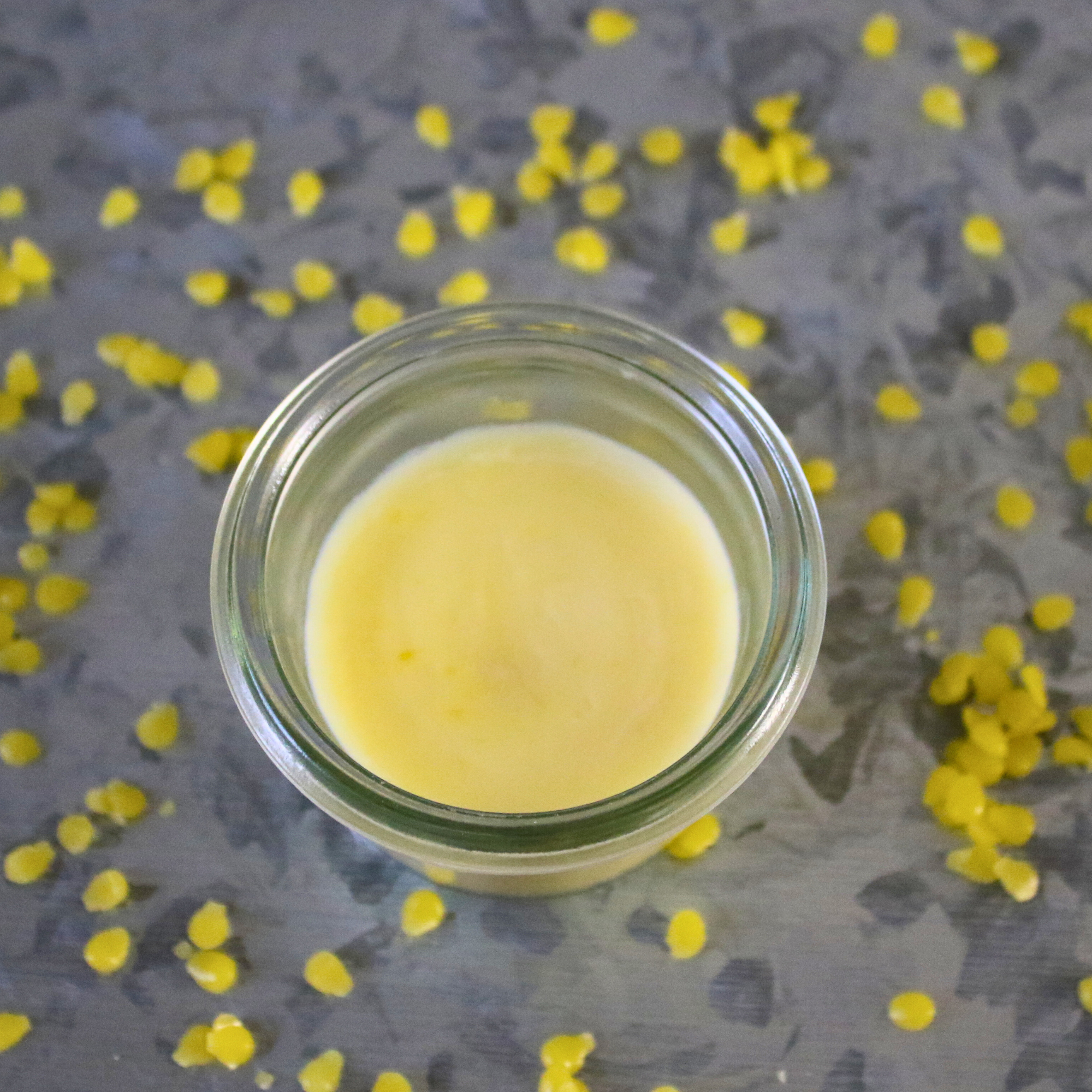 Coconut oil cuticle cream in a glass jar, surrounded by beeswax.
