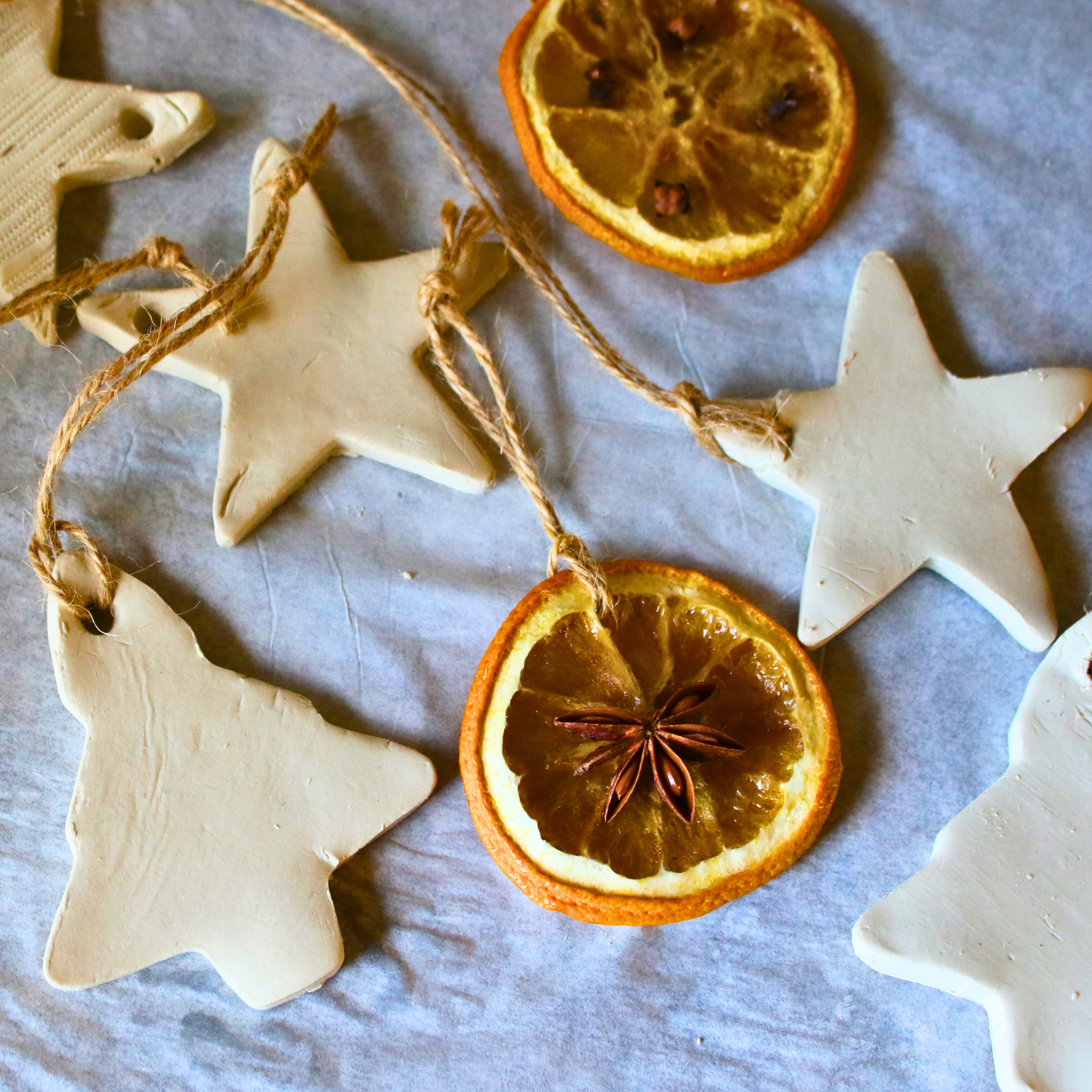Homemade diffuser ornaments made of clay next to dried orange ornaments.