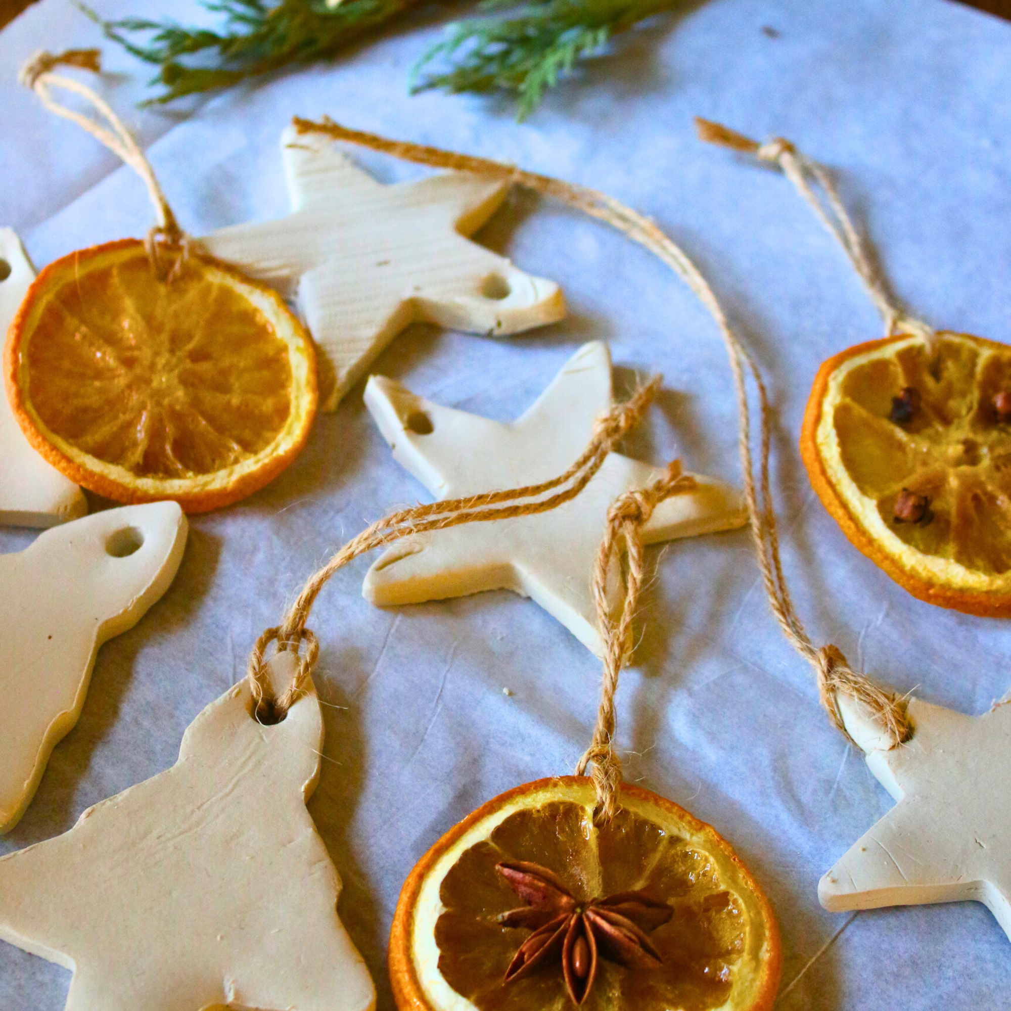 Homemade diffuser ornaments made of clay next to dried orange ornaments.