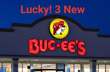 Buc-ee's lit up sign at night. Text above reads: "Lucky! 3 New" - followed by the Buc-ee's logo and "Buc-ee's"