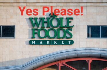 Whole Foods Market logo on a building with "Yes Please!" written above it in orange letters