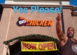 Shaq pointing up at "Yes Please" in from of a Big Chicken restaurant with a "Now Open" sign.