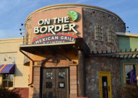 Exterior of On The Border Mexican Grill and Cantina with stone facade and colorful awning.