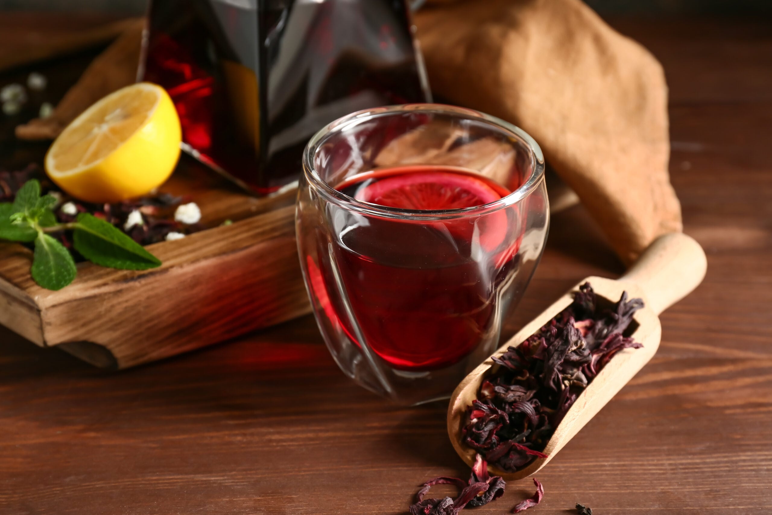 A glass of hot hibiscus tea on a wooden table.