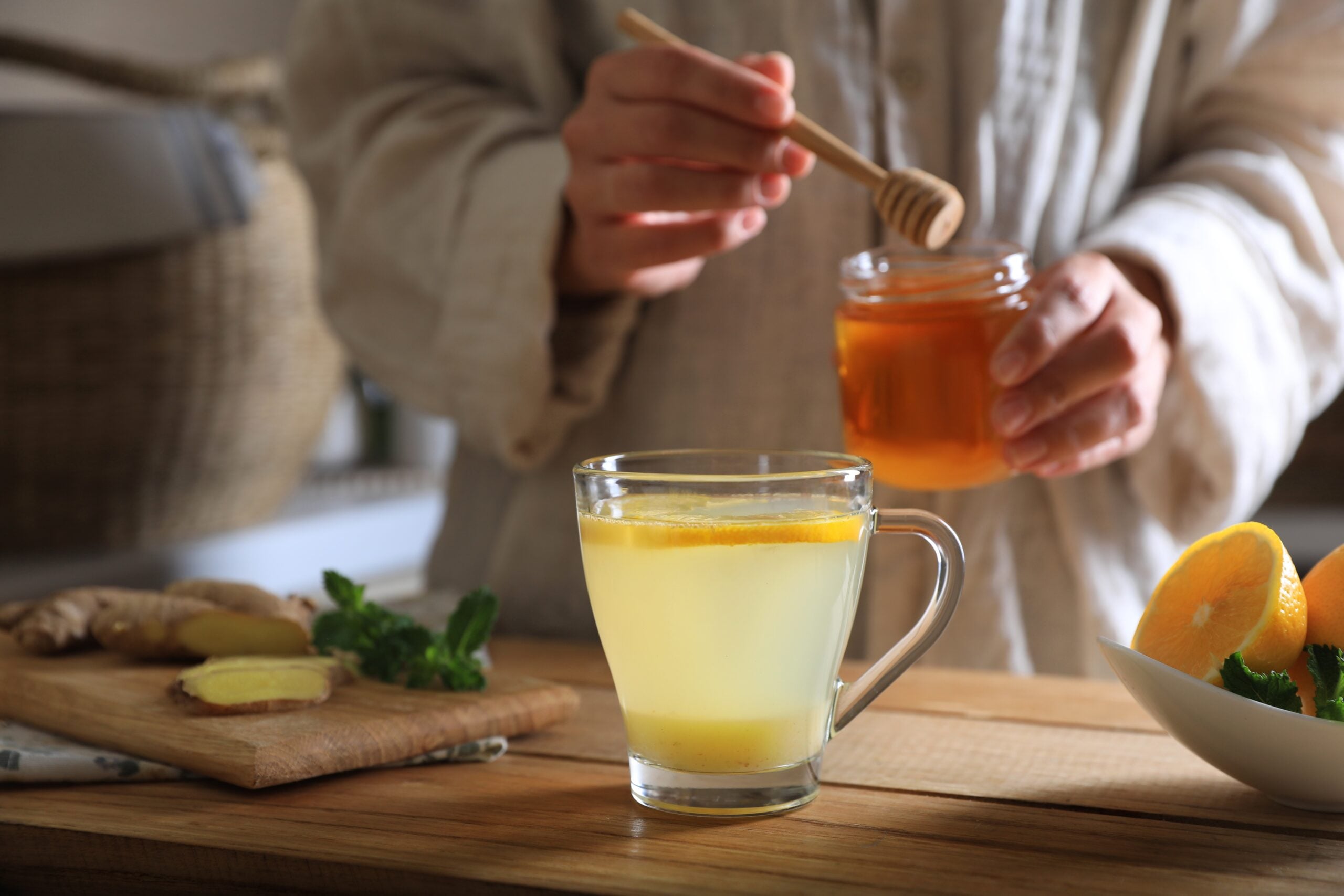 A woman preparing a honey lemon tea. 