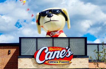 Raising Cane's sign with a big inflatable dog above it