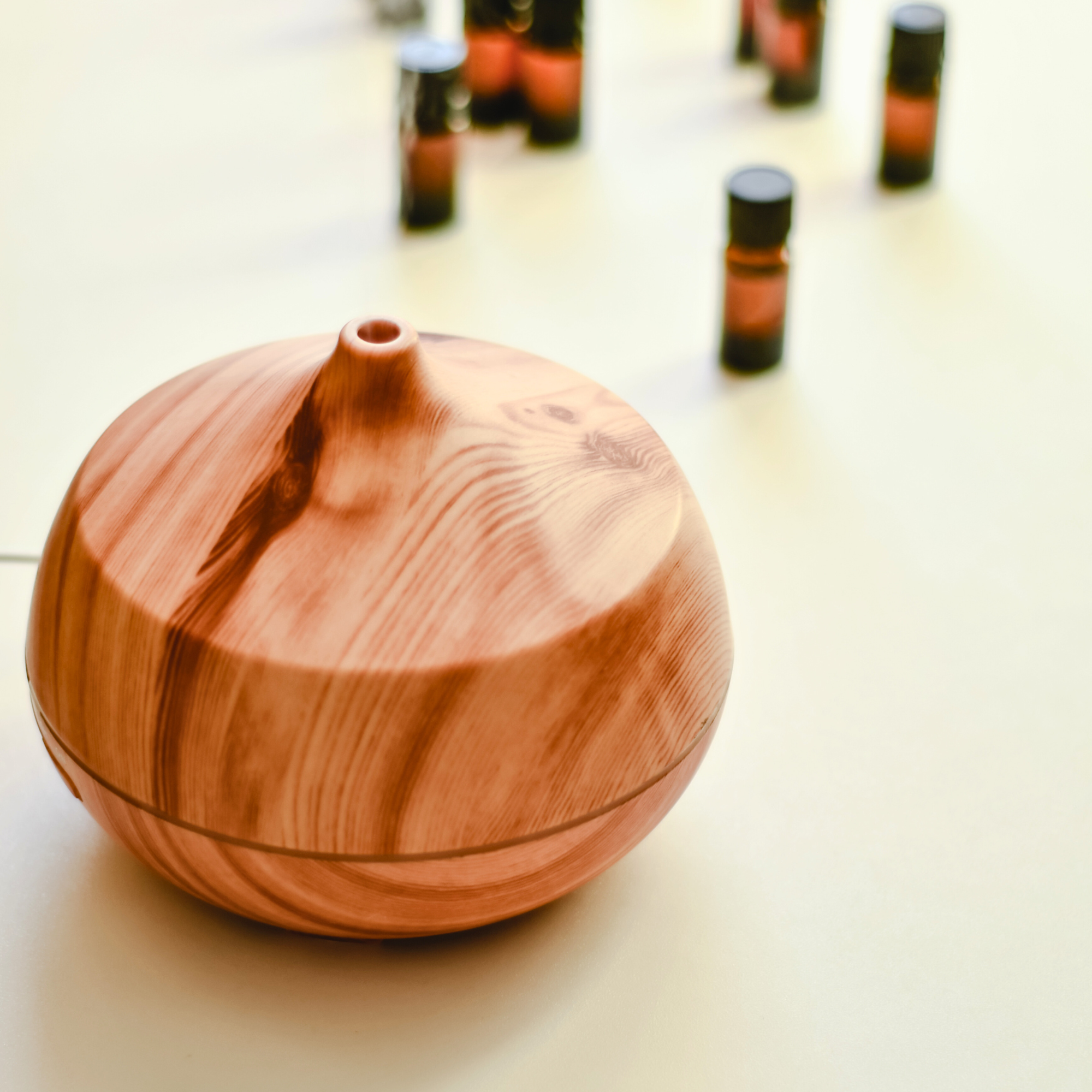 A wooden essential oil diffuser with a few bottles of essential oils next to it.