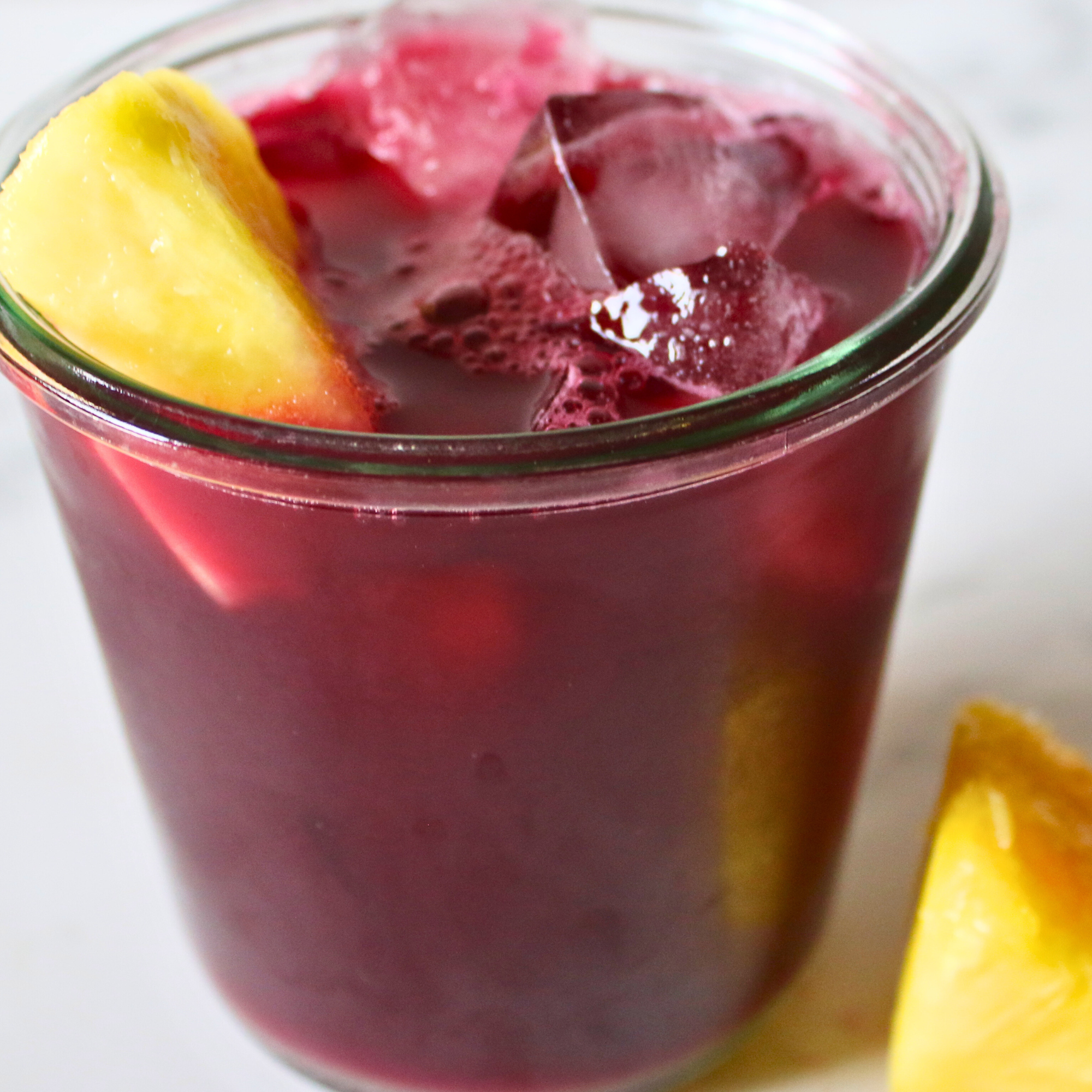 A glass jar of cranberry, pineapple, and apple cider vinegar, garnished with fresh pineapple.