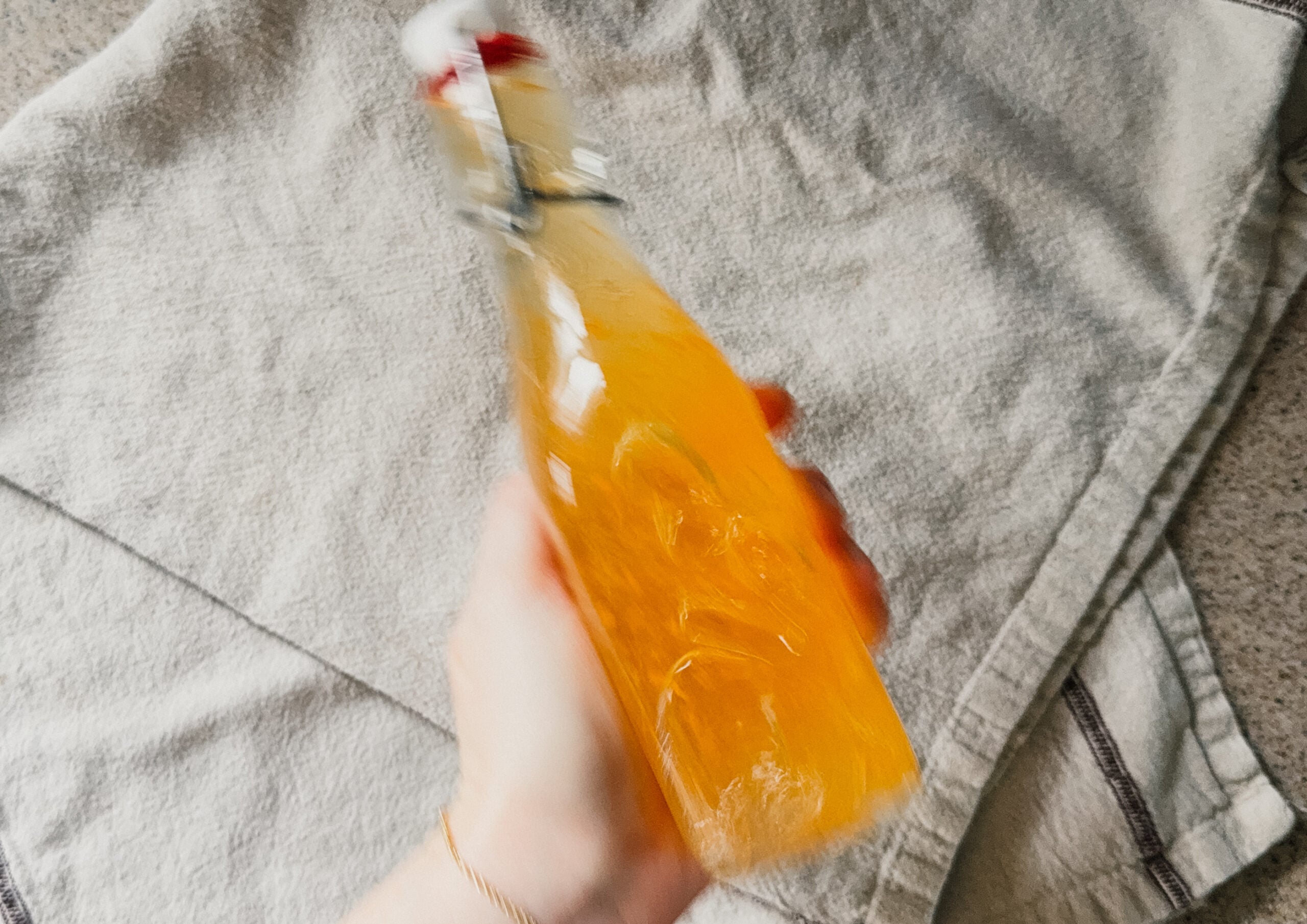 A hand actively shaking a bottle of turmeric and apple cider vinegar.