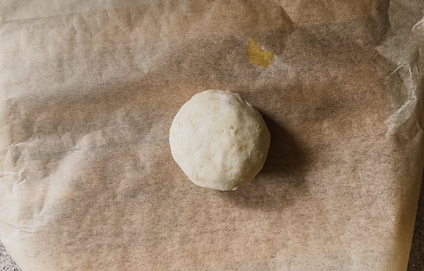 A ball of dough on top of a piece of parchment paper.