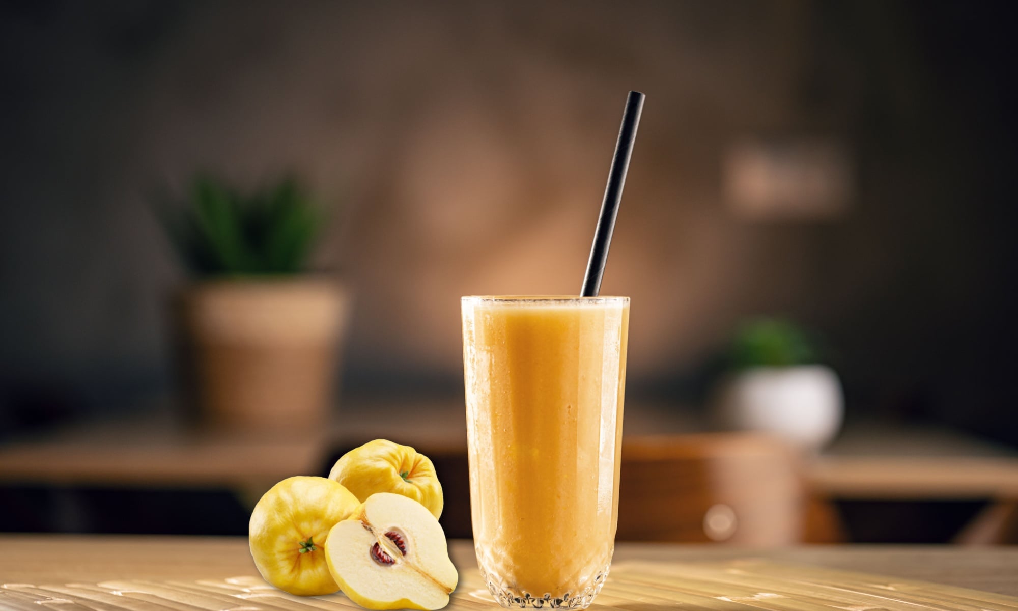 A quince smoothie and a few fresh quinces againsta a blurry backdrop. 
