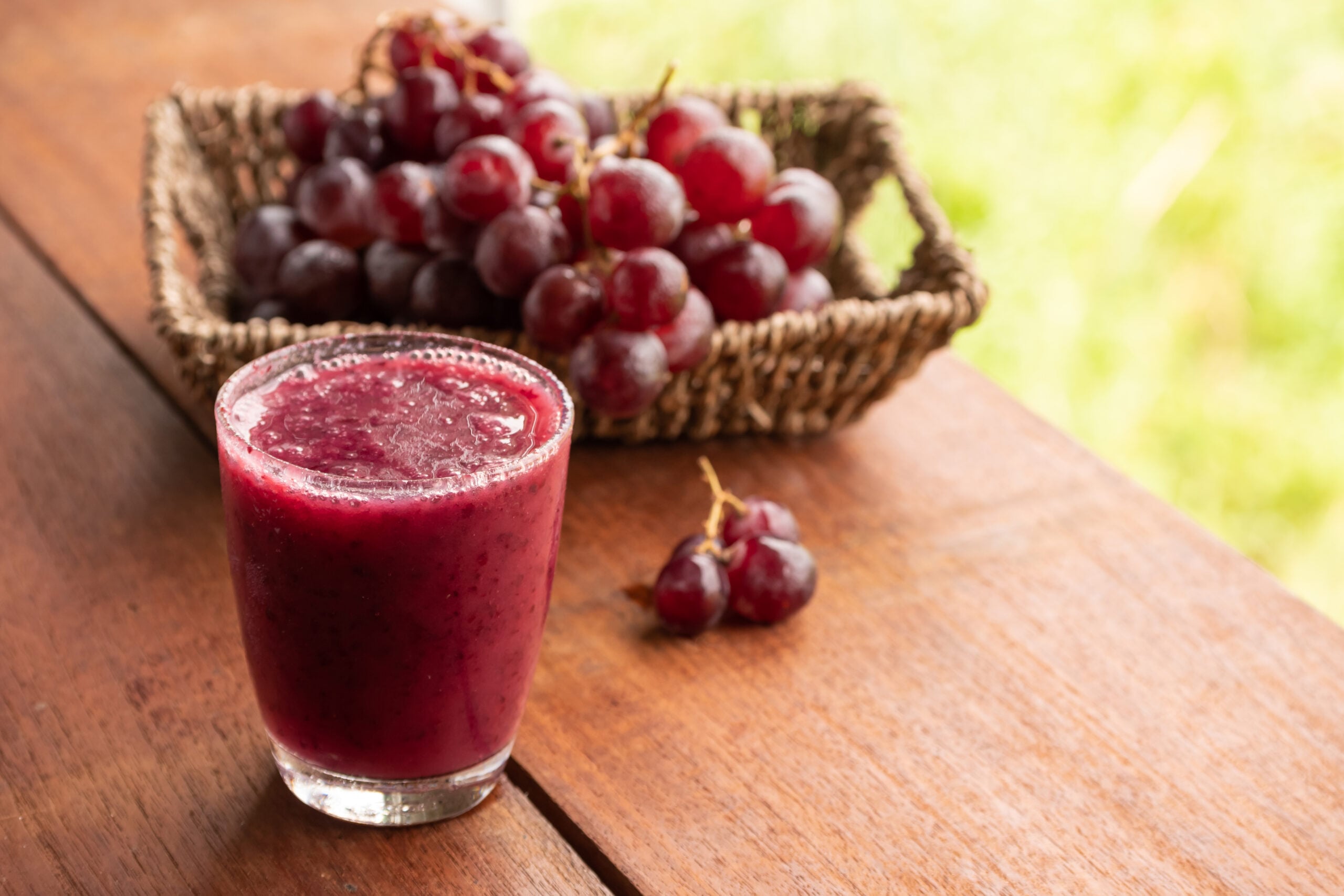 A refreshing purple grape smoothie, accompanied by fresh grapes. 