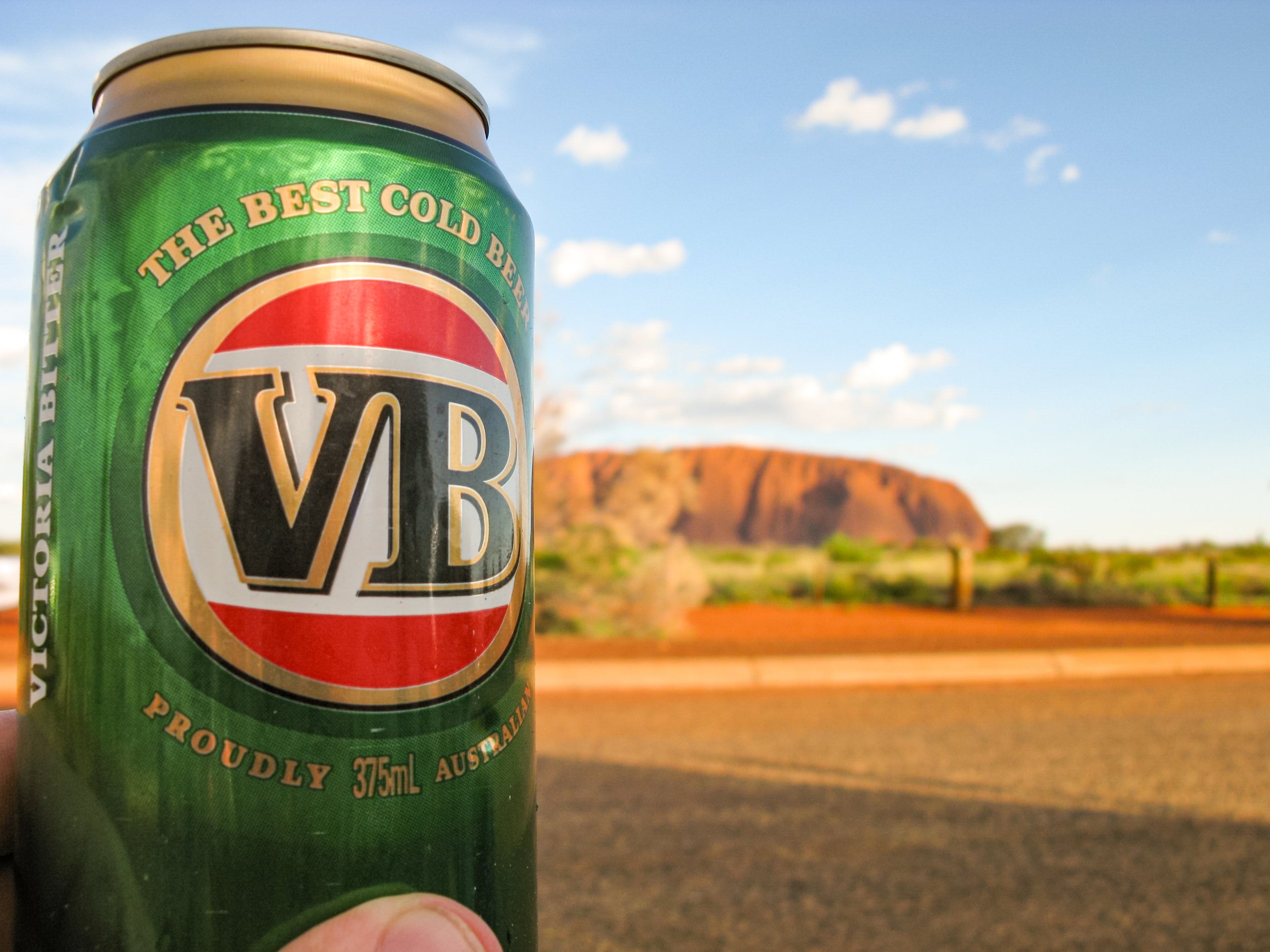 A macro shot of a person holding a can of Victoria Bitter beer