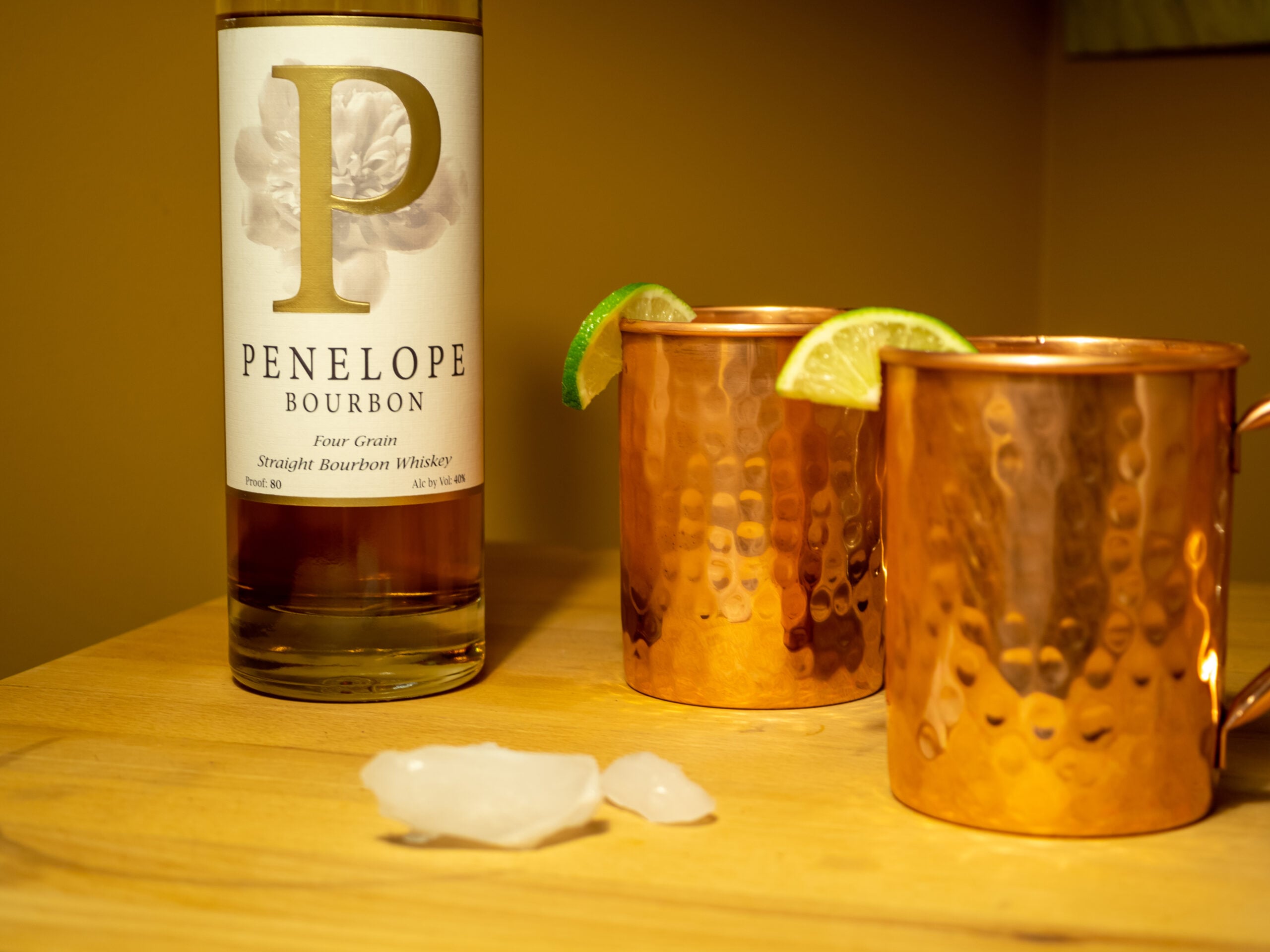 Two cooper cups containing Kentucky Mule, accompanied by a bottle of Bourbon. 