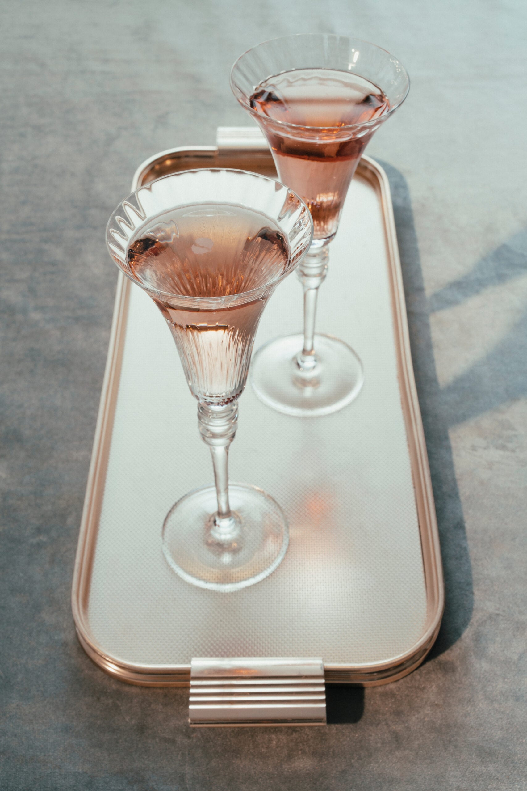 A  golden tray displaying a couple of vintage glasses of Prosecco Rosé.
