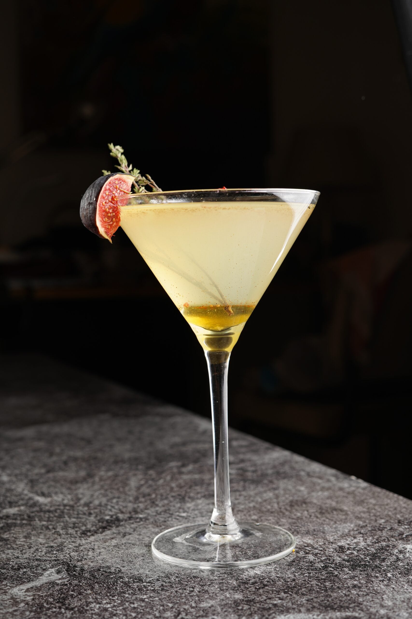 A dark backdrop featuring a glass of Quarantini. 