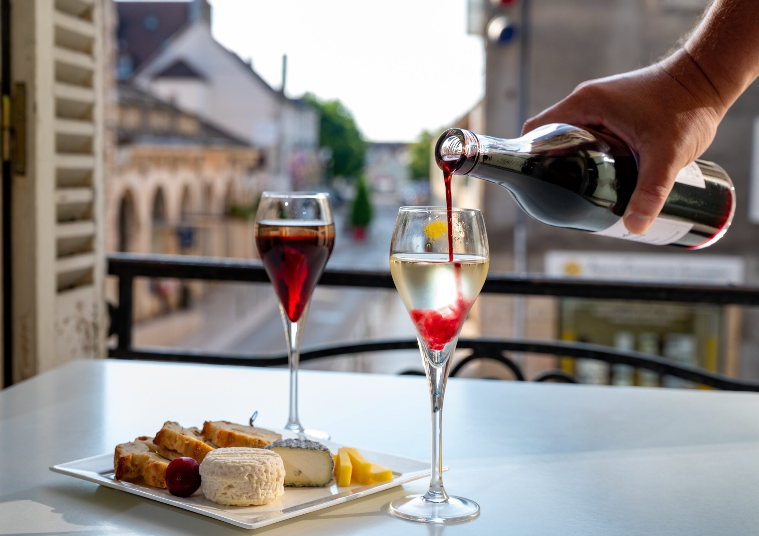 In Paris, a man is making a Kir drink beside a window.  