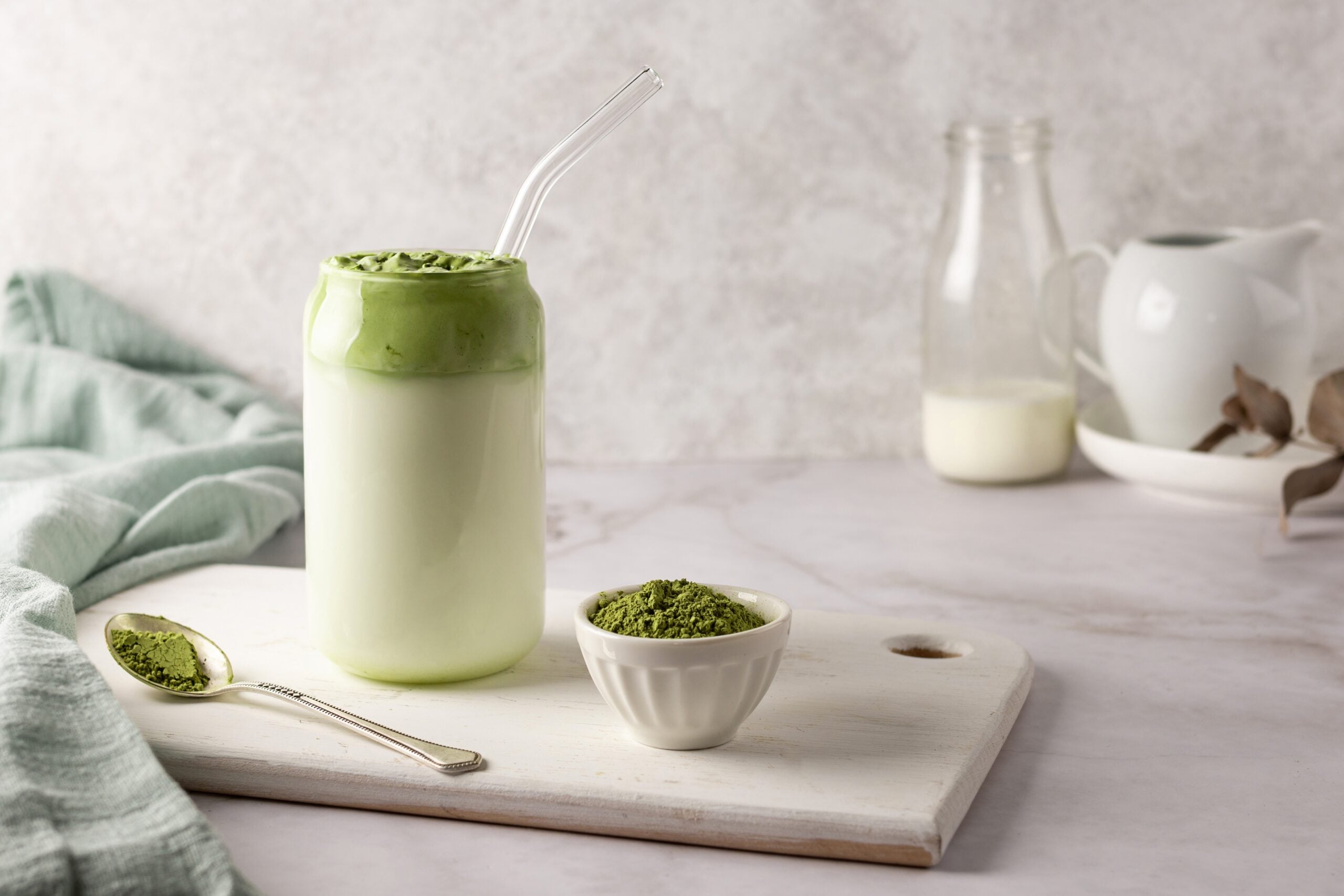 A refreshing matcha latte, surrounded by its ingredients. 