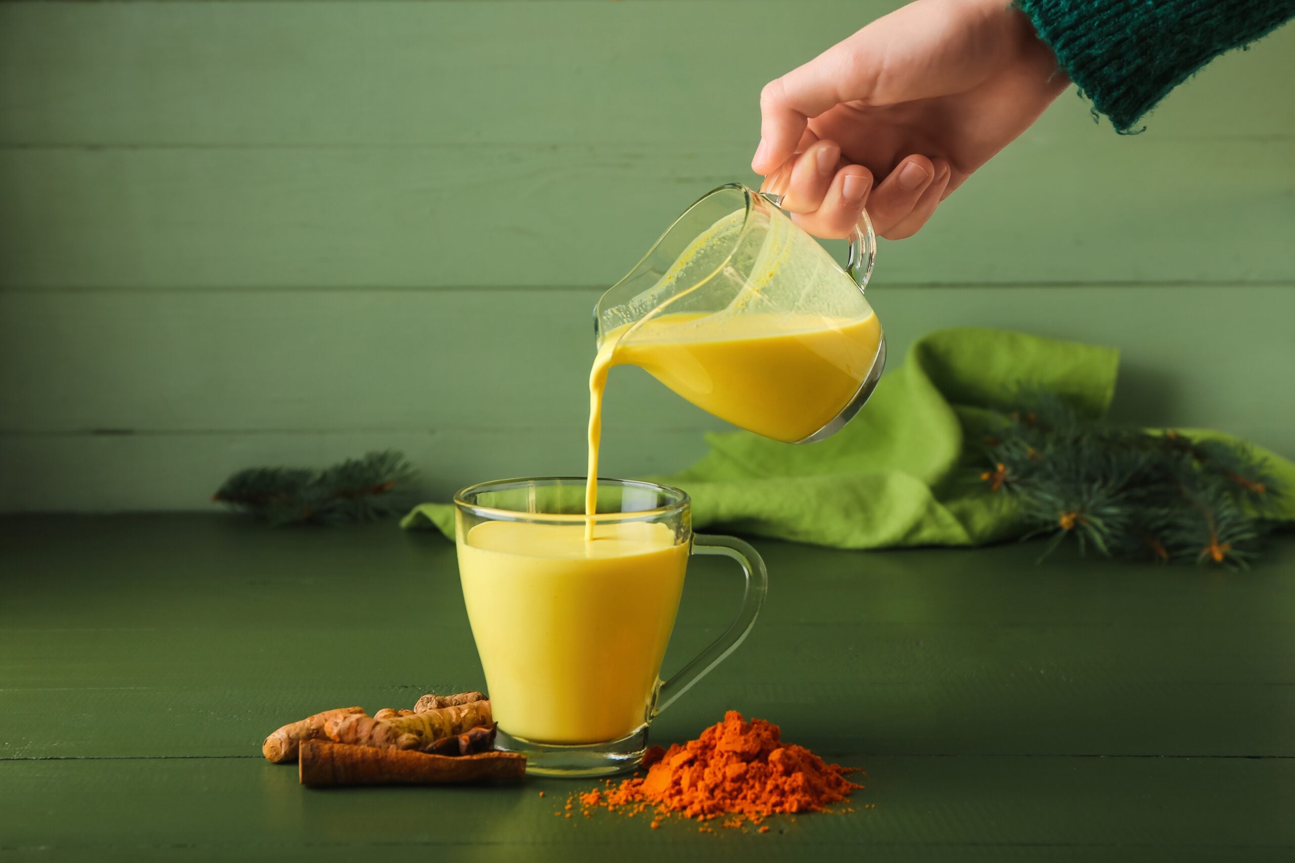 A woman serving turmeric latte into a cup. 