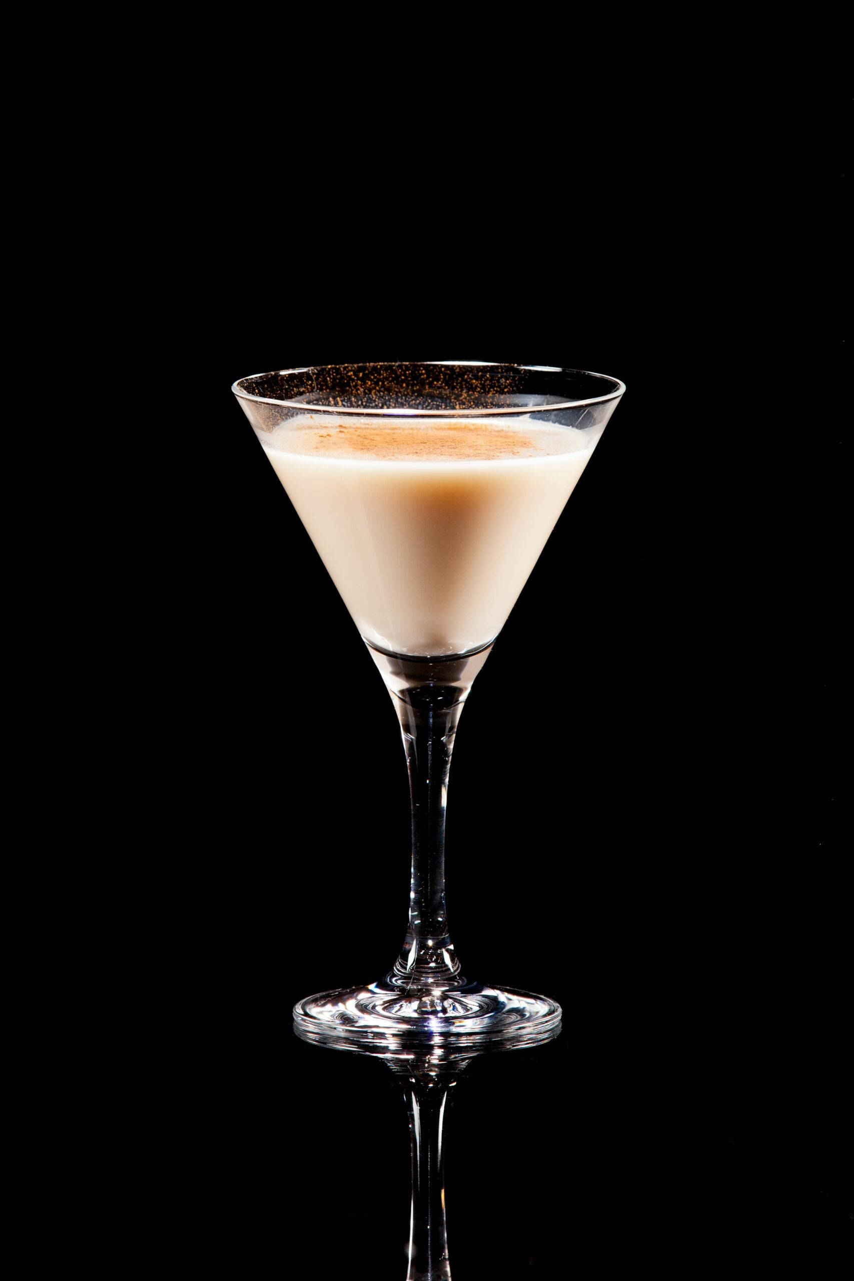 A black backdrop featuring a single glass of velvel hammer cocktail. 