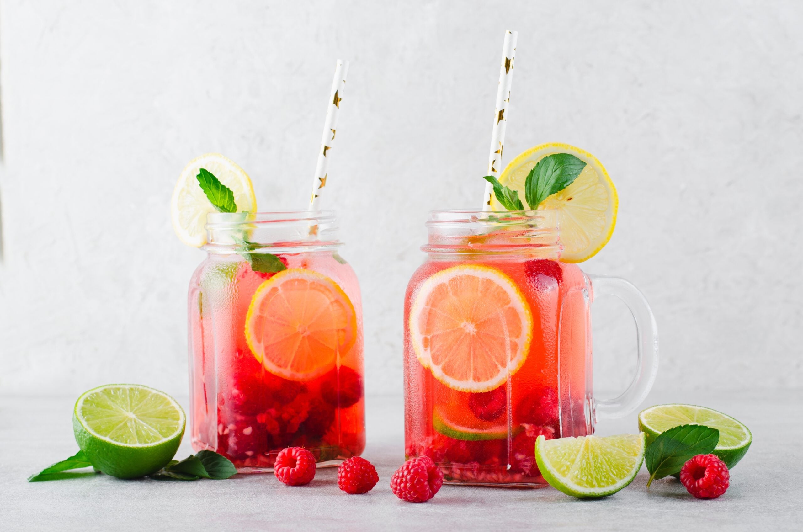 A pair of quick berry lemonade mugs surrounded by fresh berries and limes.