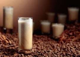 Tall glass of iced coffee on coffee beans.