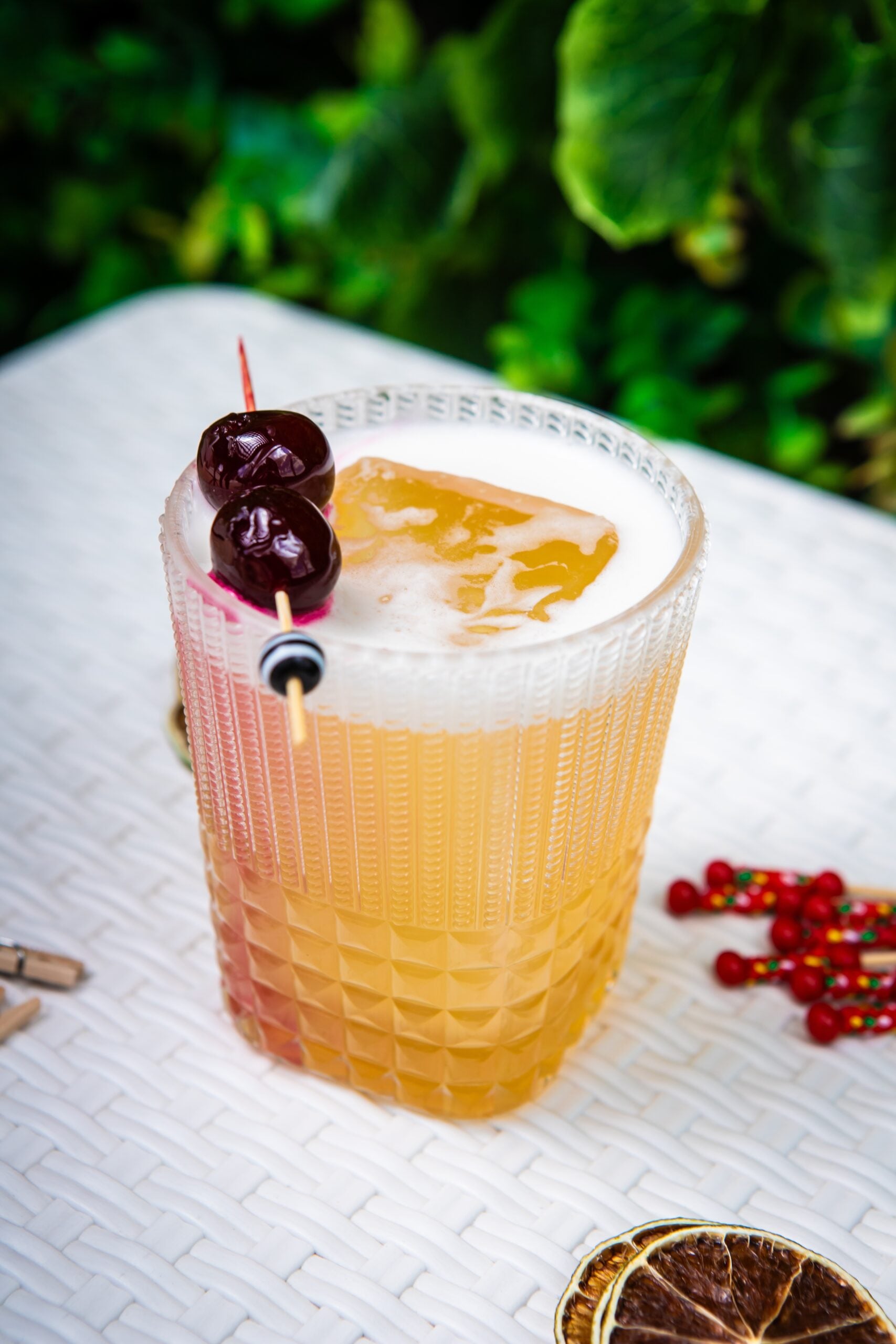 A single glass of twisted whiskey sour topped with cherries.