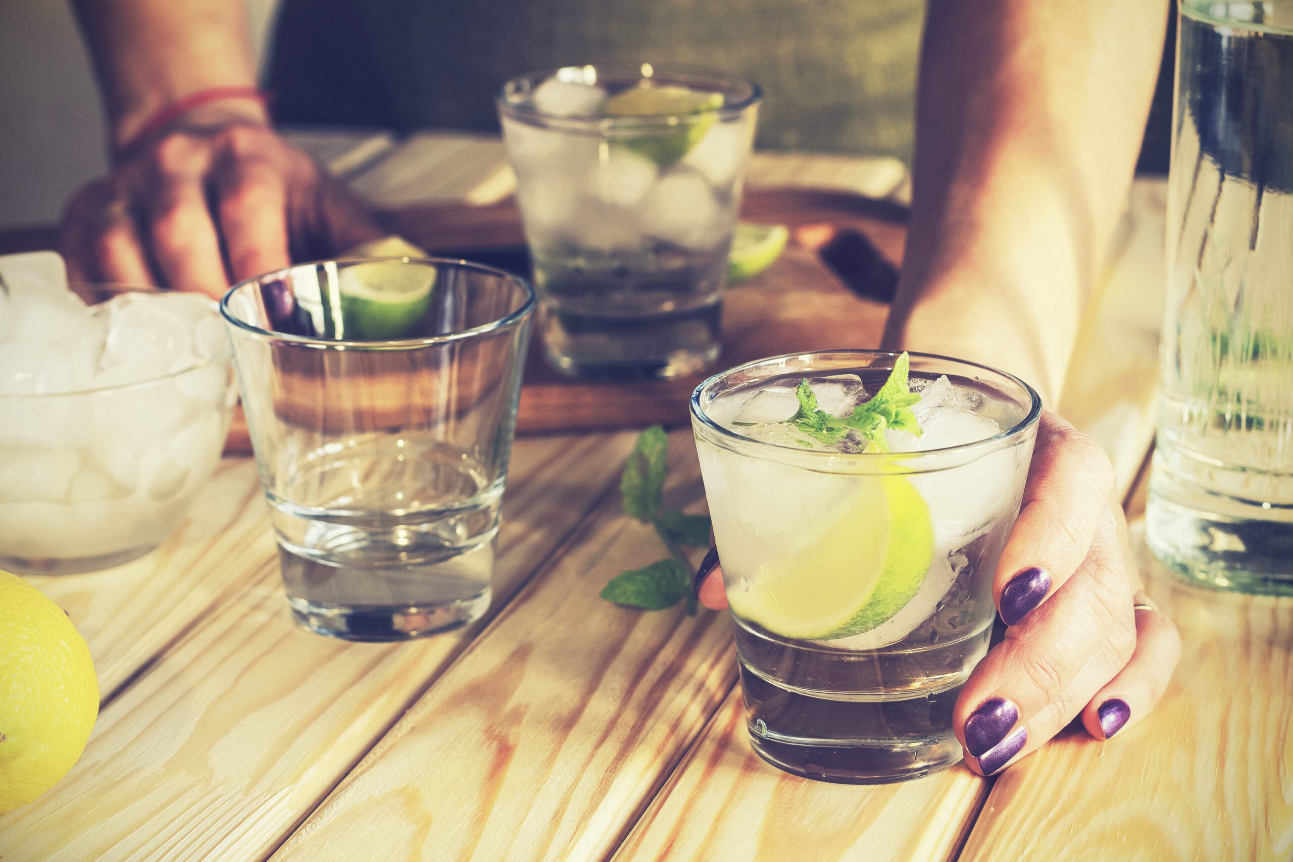 A woman preparing tequila mojitos on a wooden table