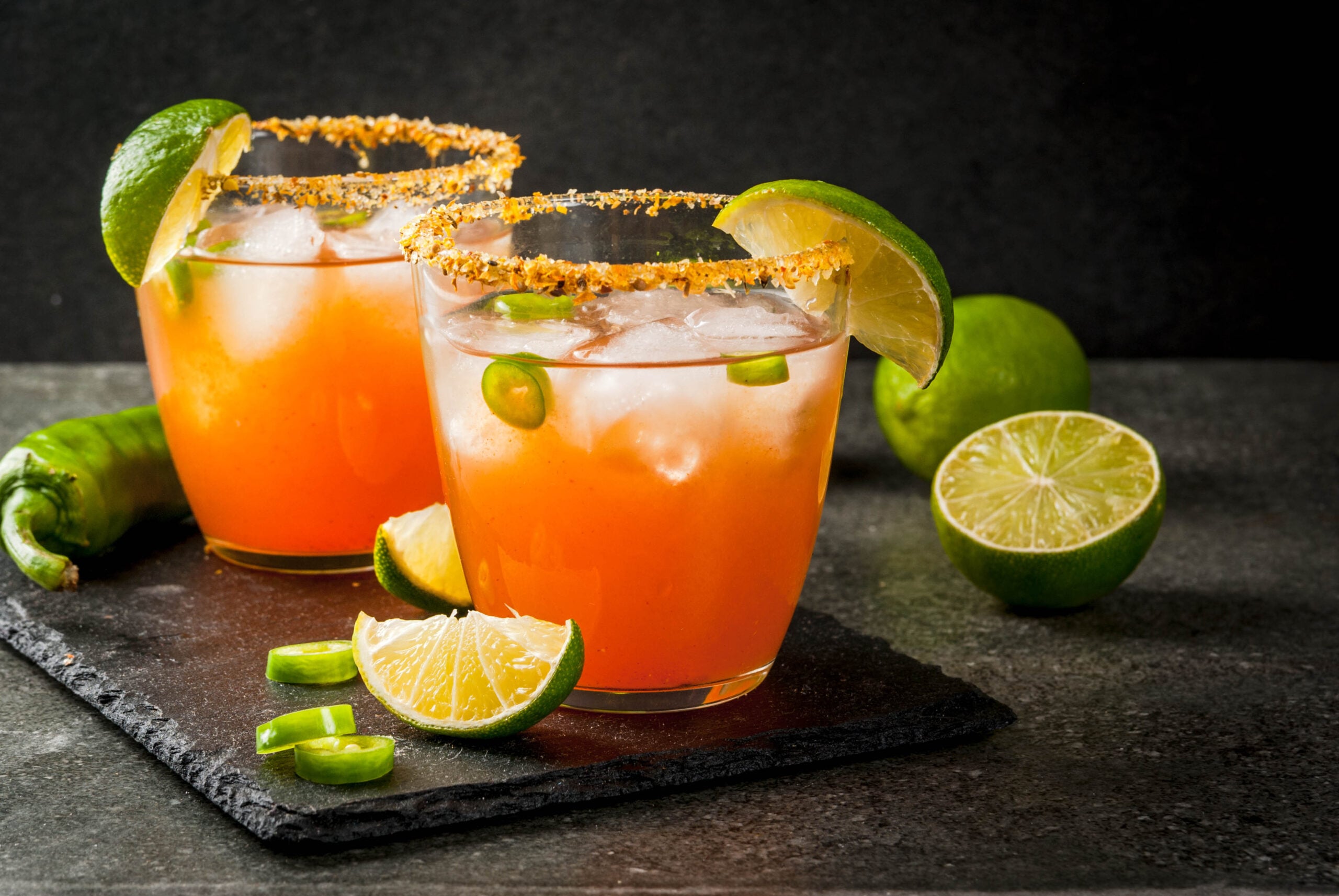 A concrete surface featuring two glasses of  traditional Mexican Michelada.