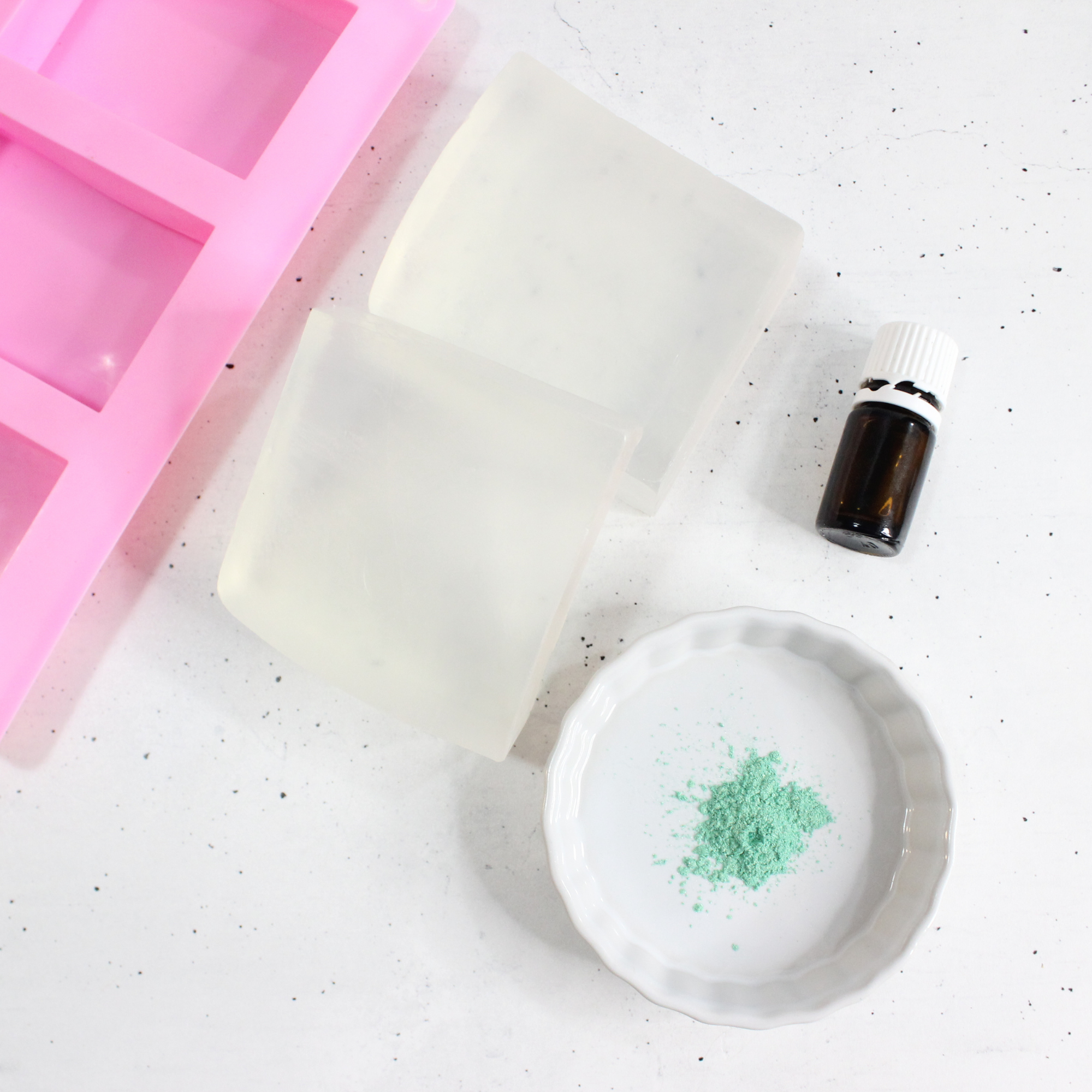 Glycerin soap, essential oils, and mica powder, next to a soap bar mold.