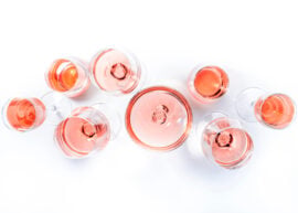 Top view of multiple glasses filled with rosé wine on a white background.